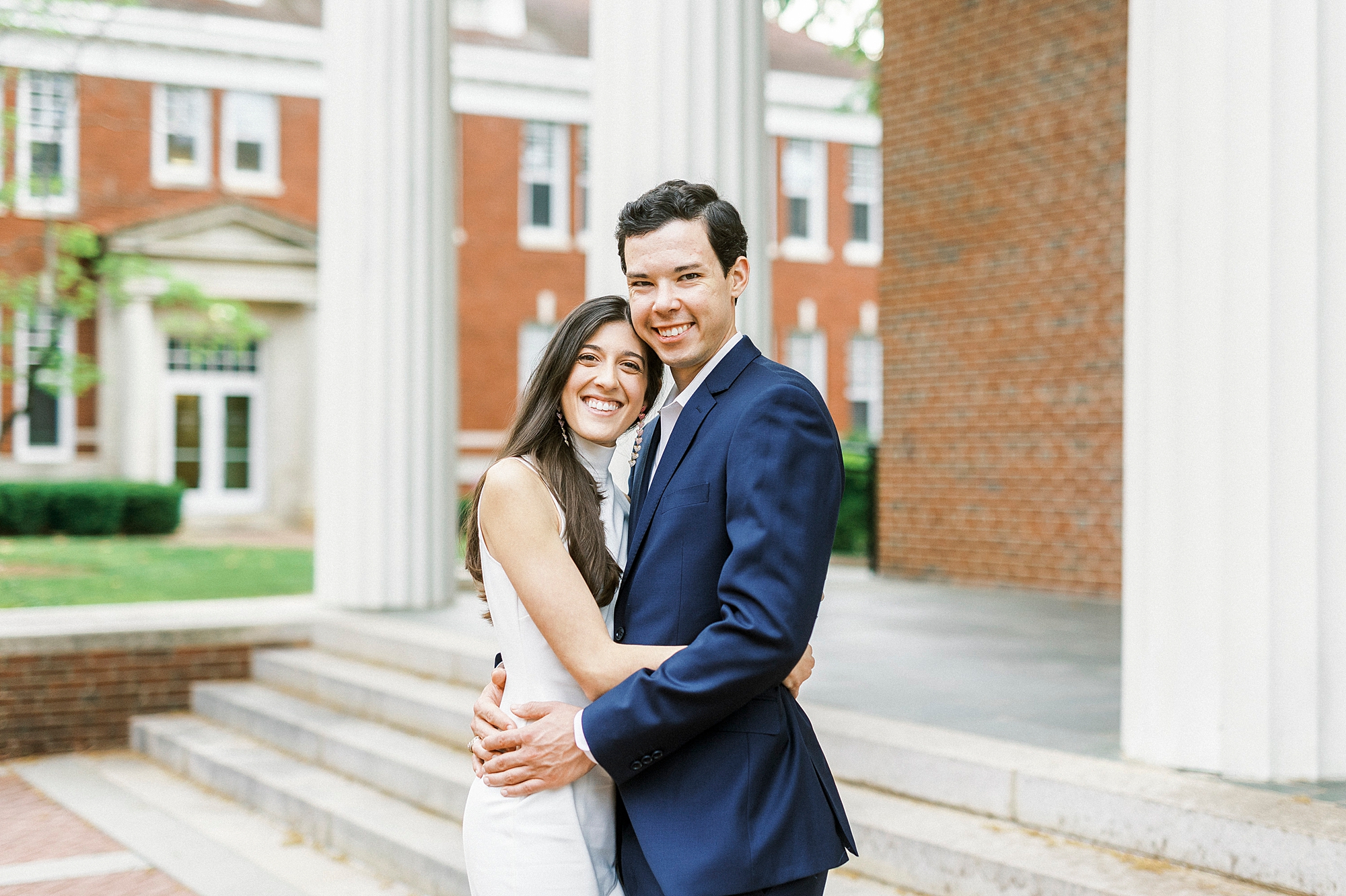 bride and groom hug on steps of Queens University
