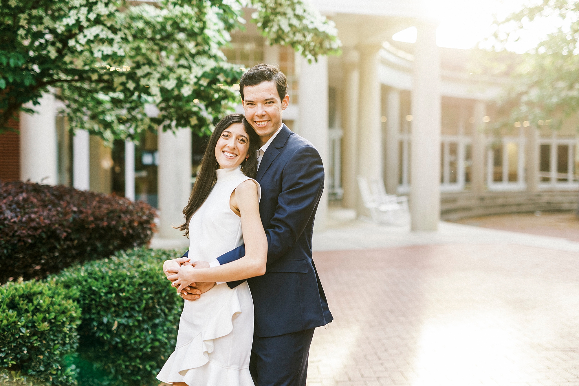 groom hugs bride from behind during engagement session at Queens University