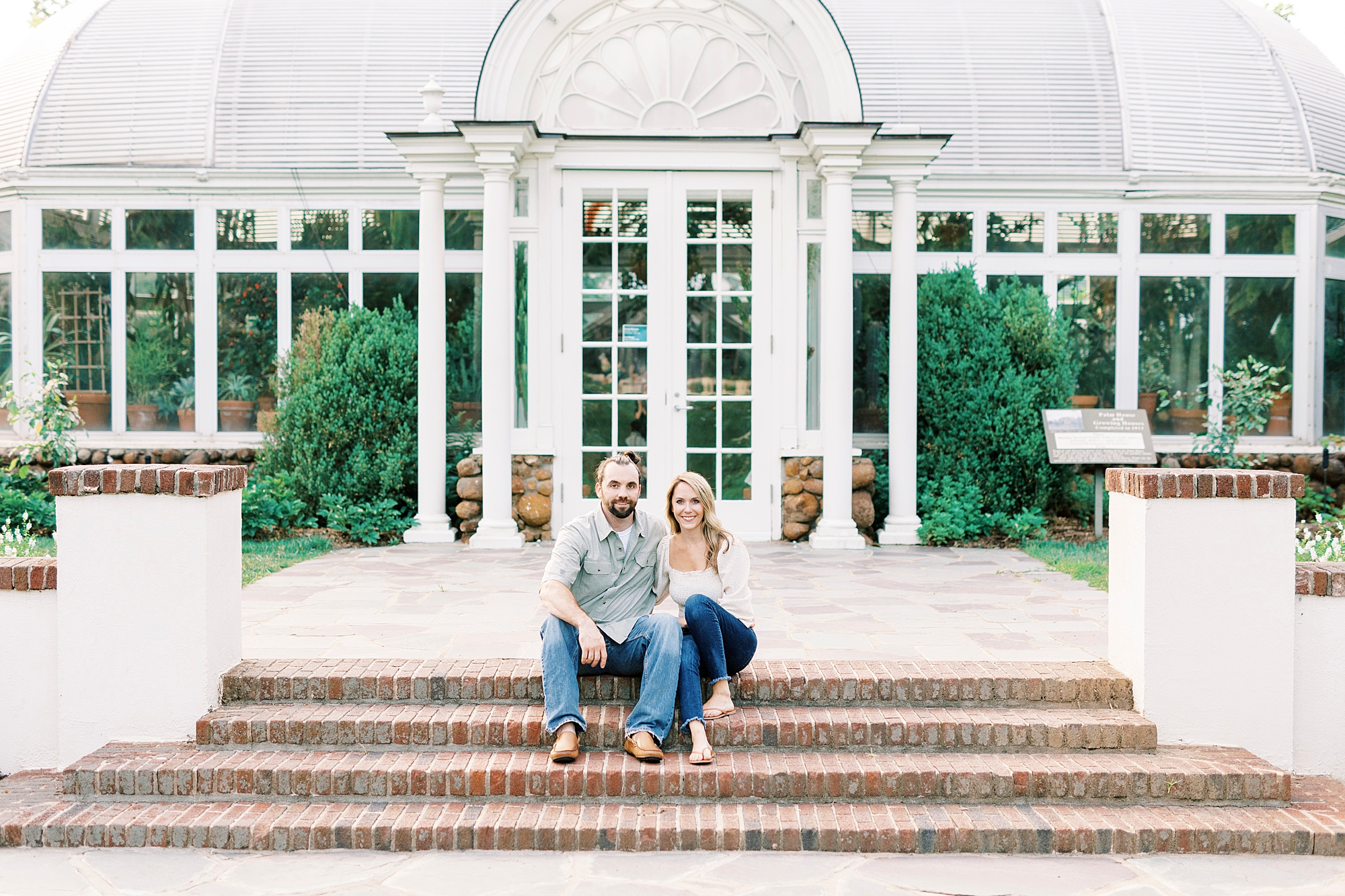 engaged couple sits on brick steps at Reynolda Gardens