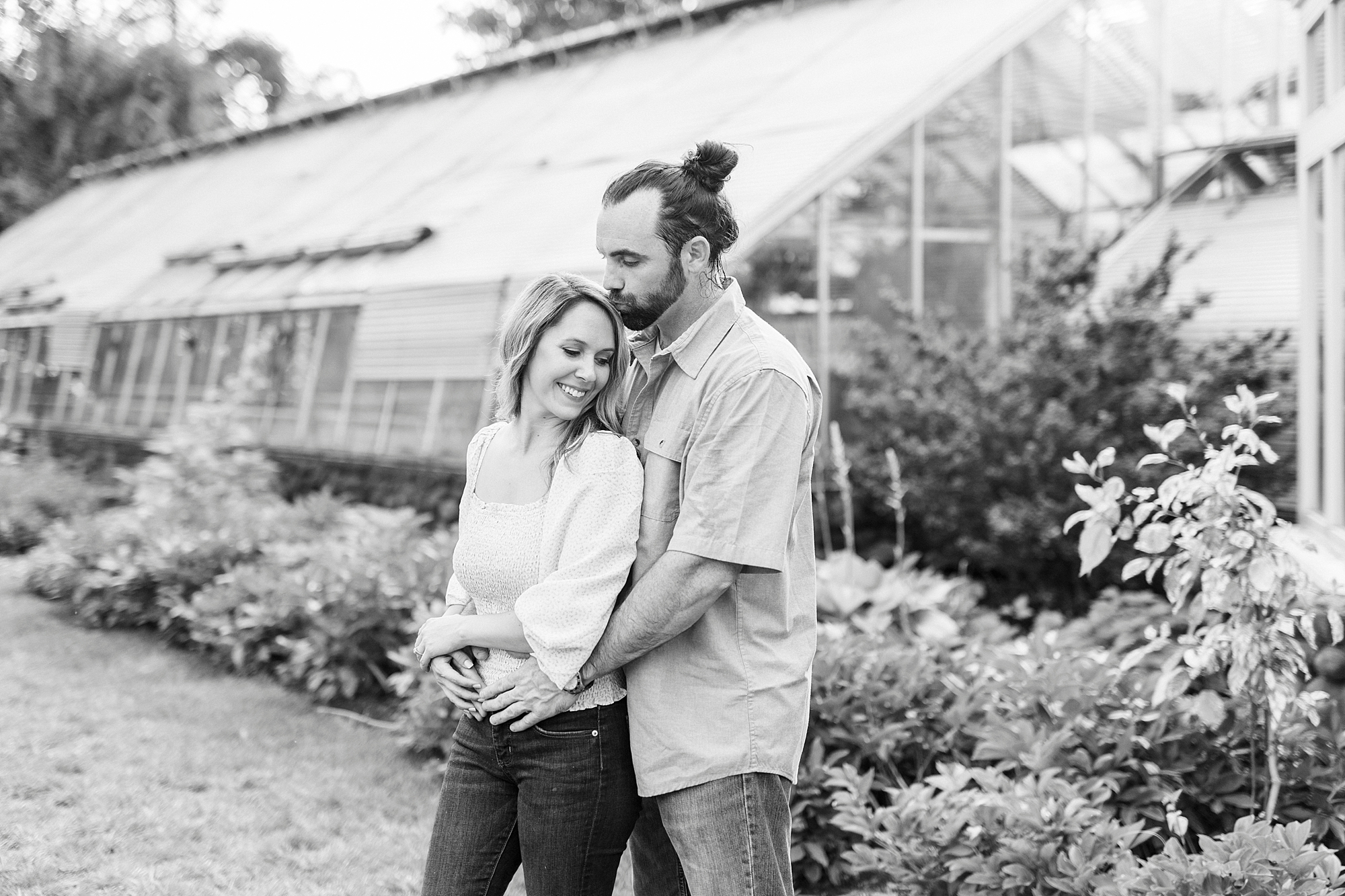 engaged couple hugs by greenhouse at Reynolda Gardens
