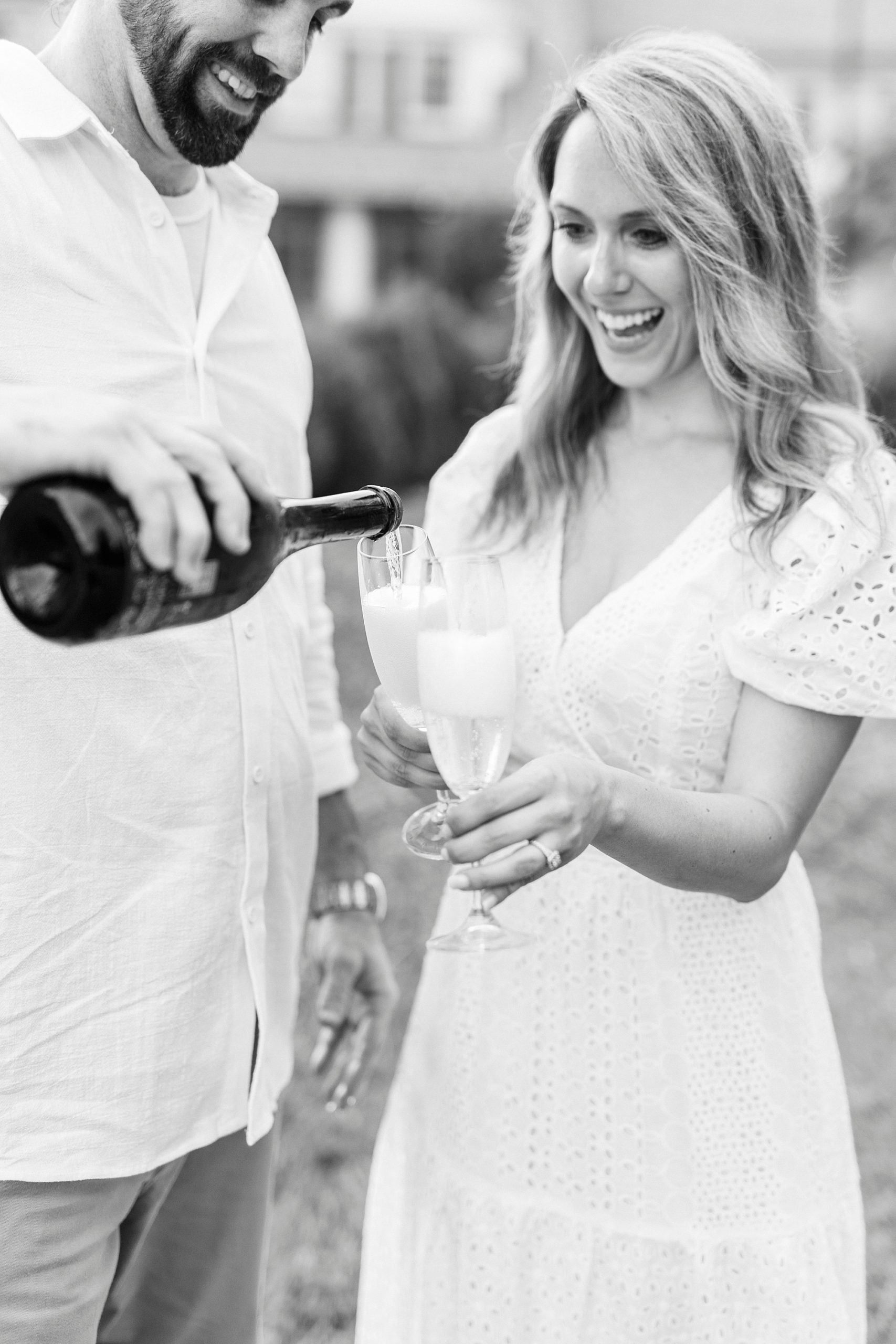 groom pours champagne for bride during Reynolda Gardens engagement photos 