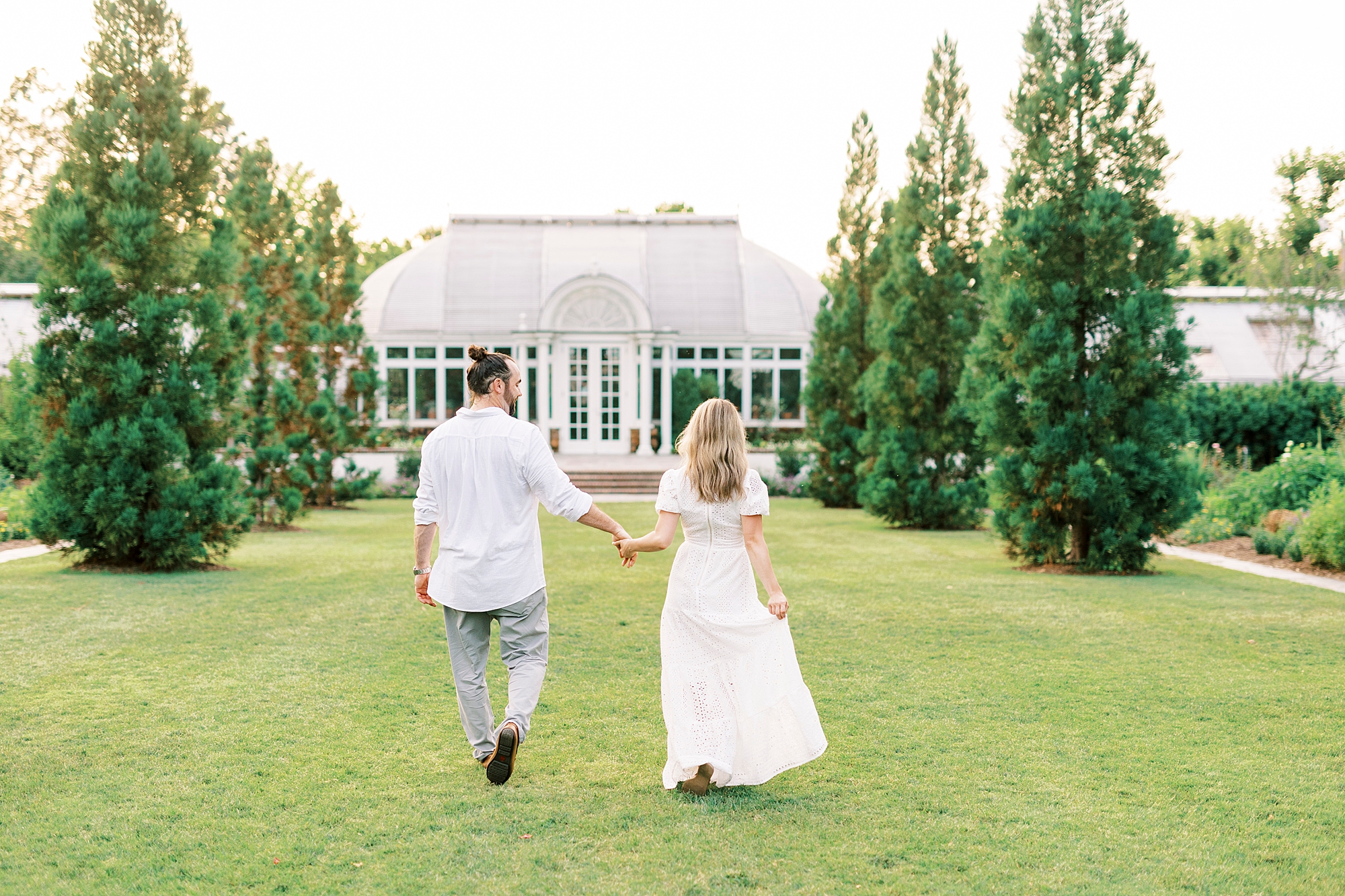 couple holds hands walking on lawn at Reynolda Gardens