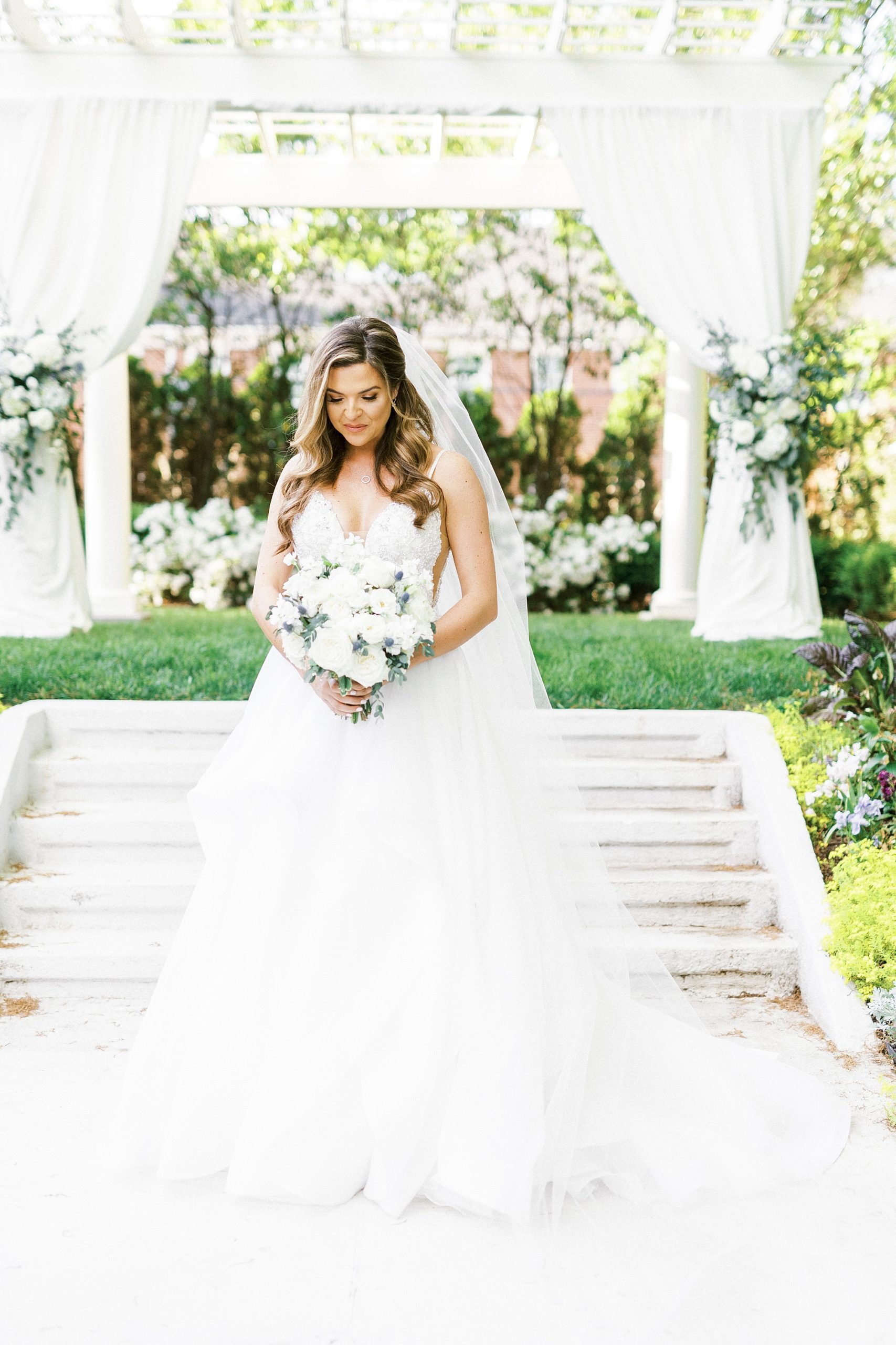 bride stands with bouquet in front of arbor at Separk Mansion