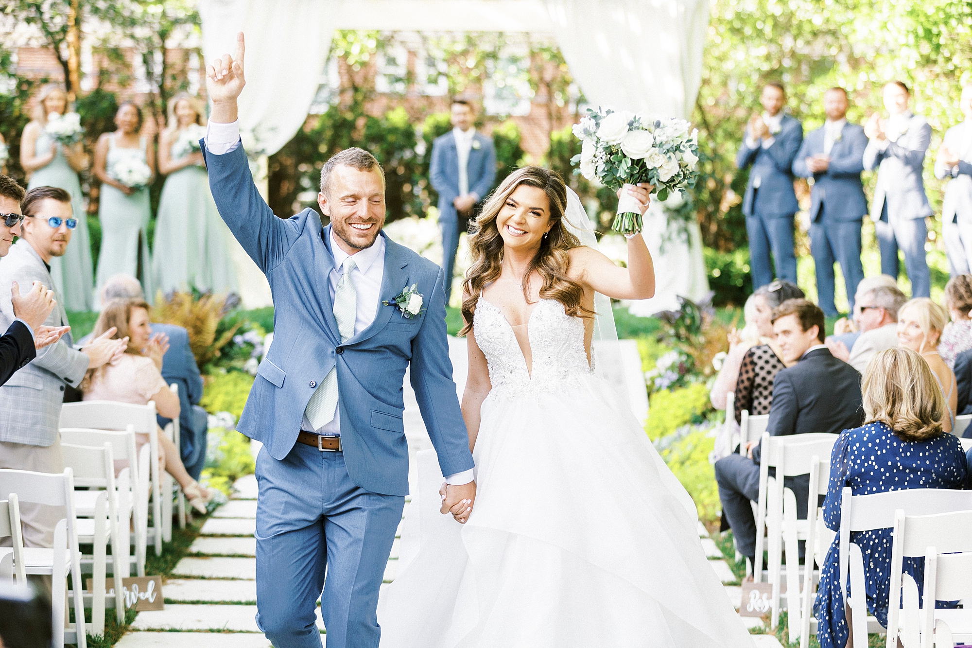newlyweds walk up aisle waving at Separk Mansion