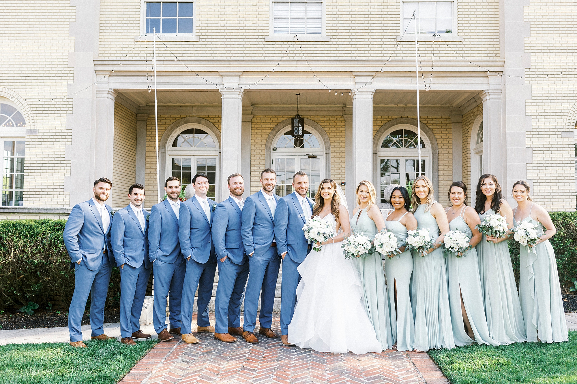 bride and groom stand with wedding party in navy and light green gowns for spring wedding day at Separk Mansion