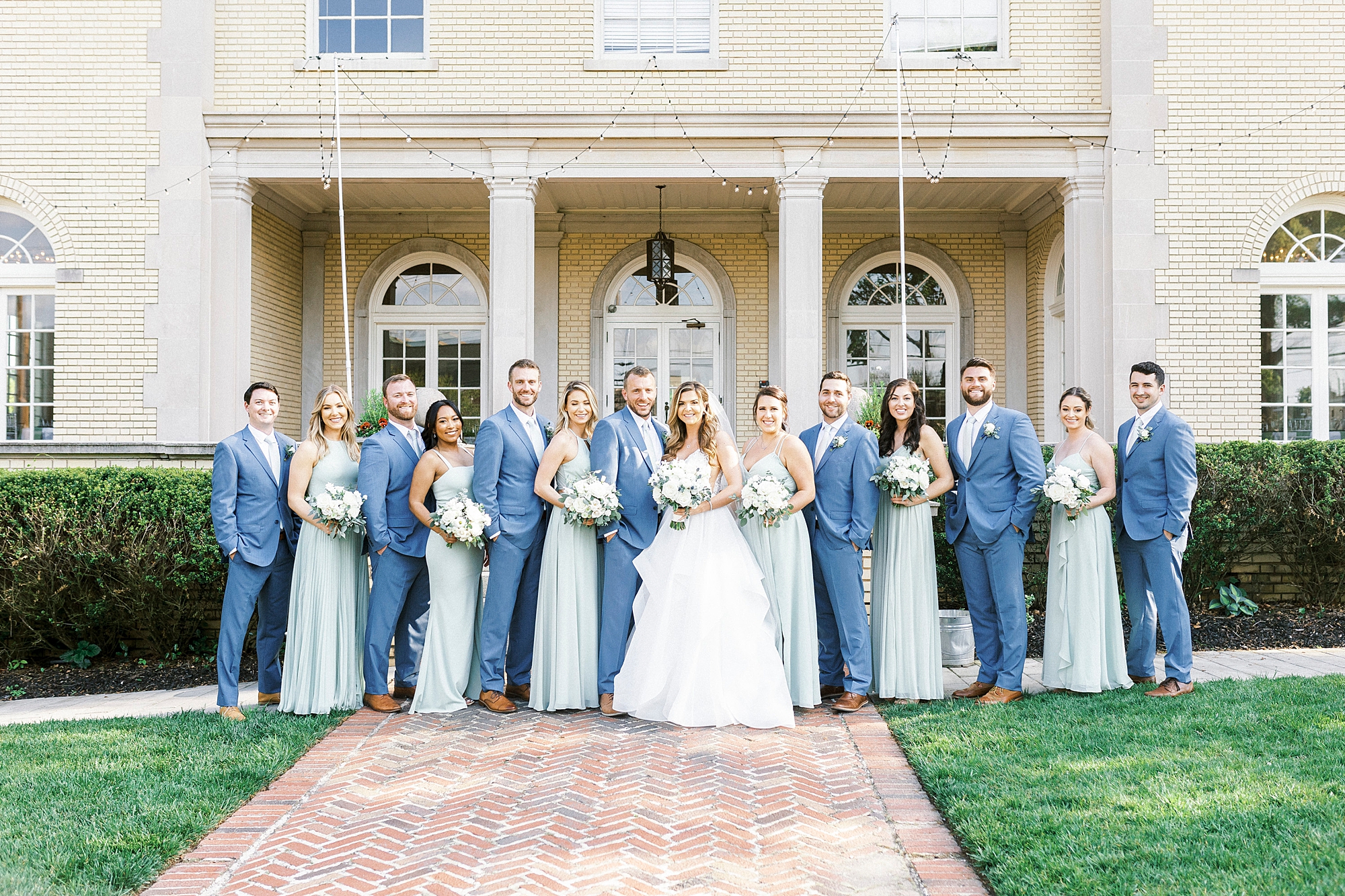 newlyweds pose with wedding party in navy and green