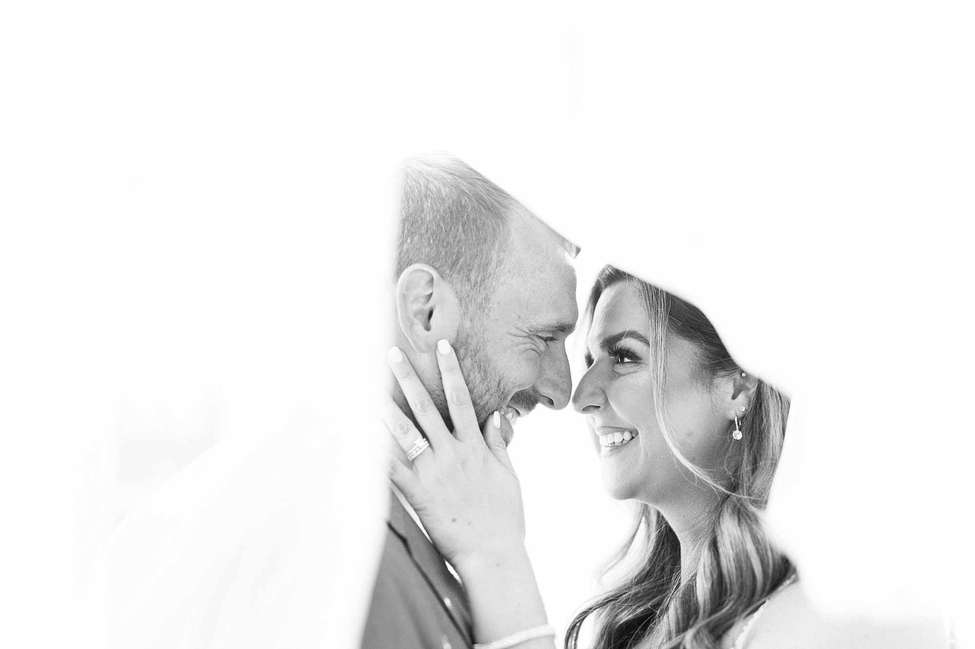 newlyweds touch noses under veil during wedding portraits 
