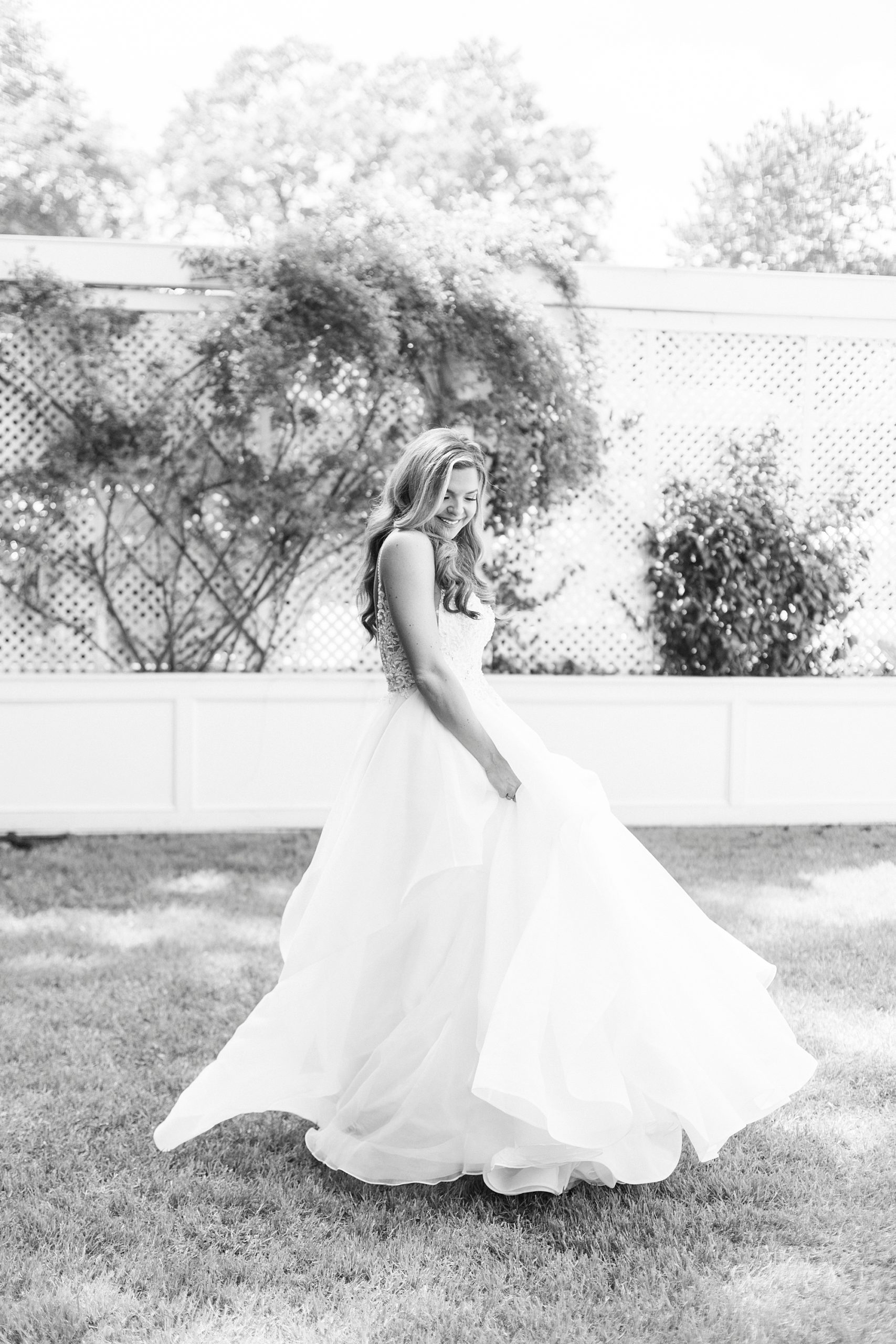black and white portrait of bride twirling wedding gown