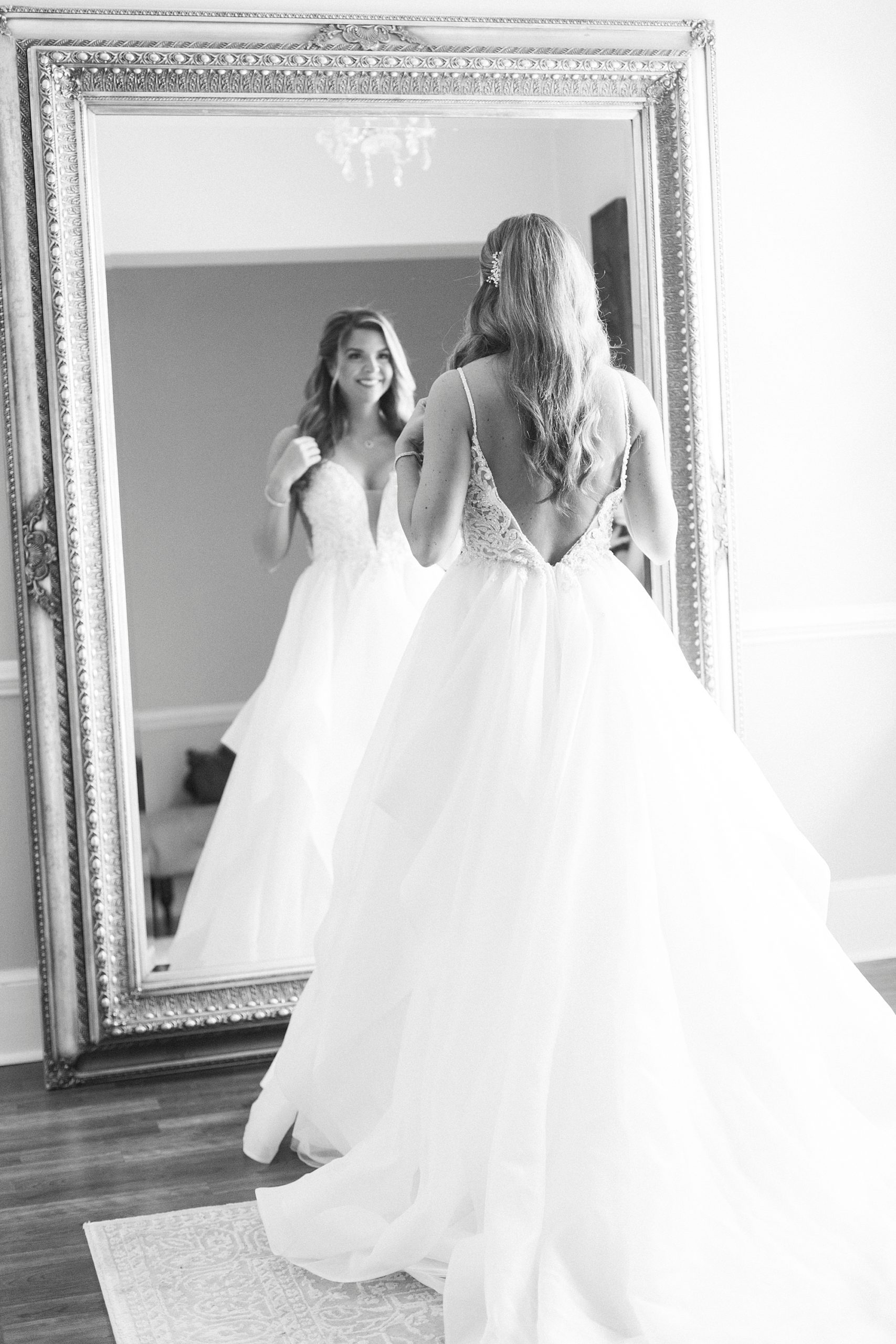 bride looks in mirror with wedding gown