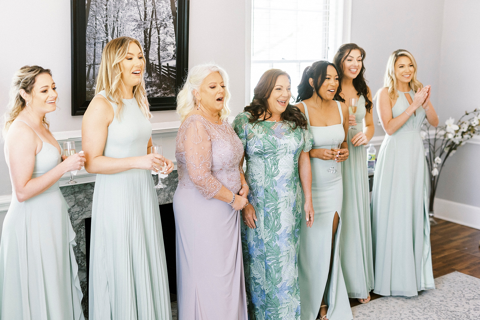 bridesmaids and mothers react to bride in wedding gown