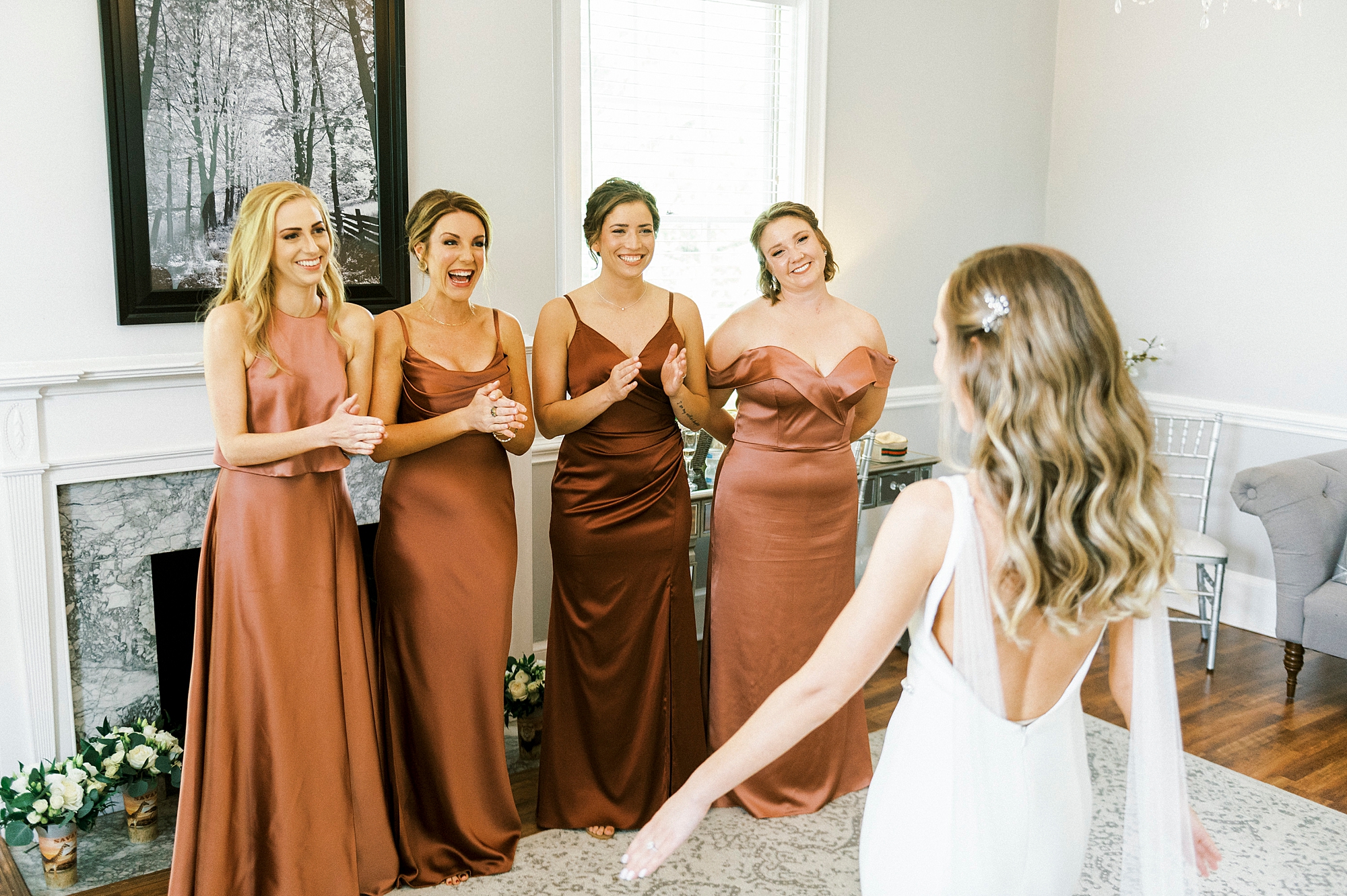bride shows off wedding gown for bridesmaids in copper gowns