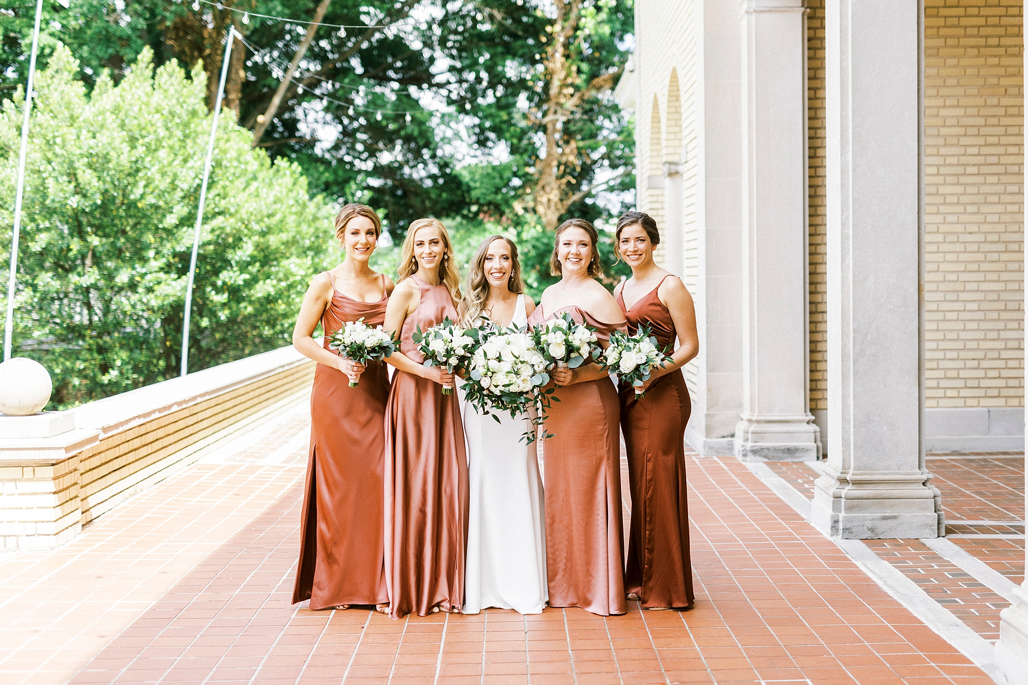 bride and bridesmaids in copper gown stand on patio at Separk Mansion