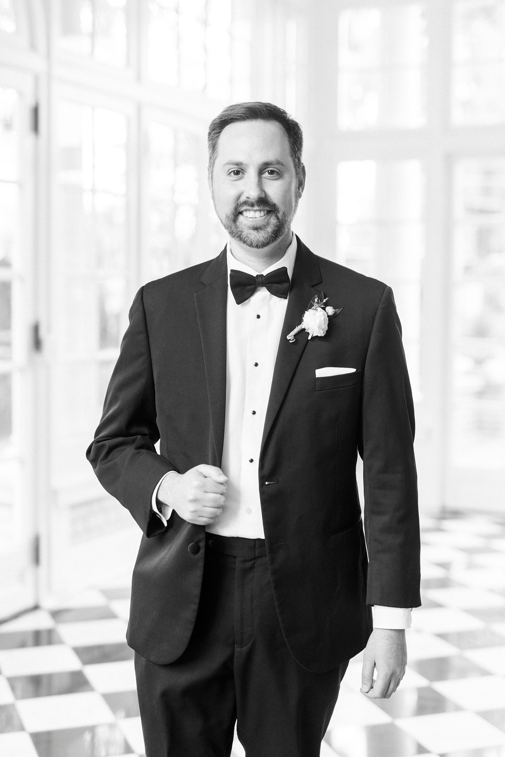 groom stands holding lapel of tux jacket for classy spring wedding