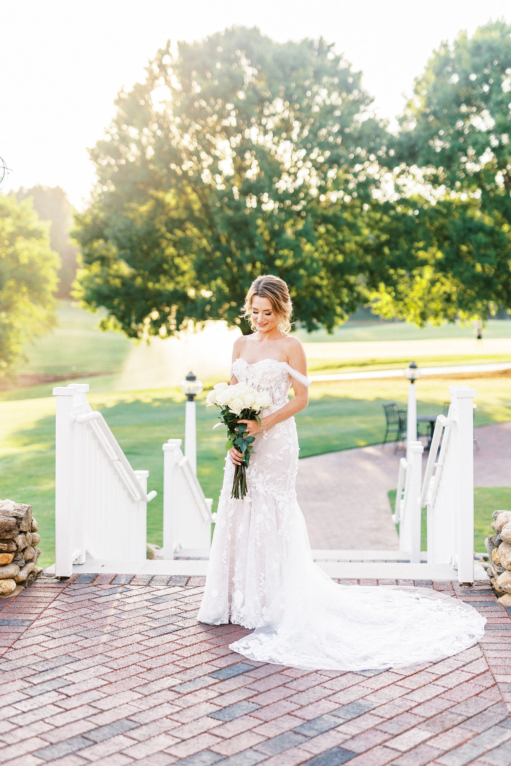 bride stands on brick patio by walkway 