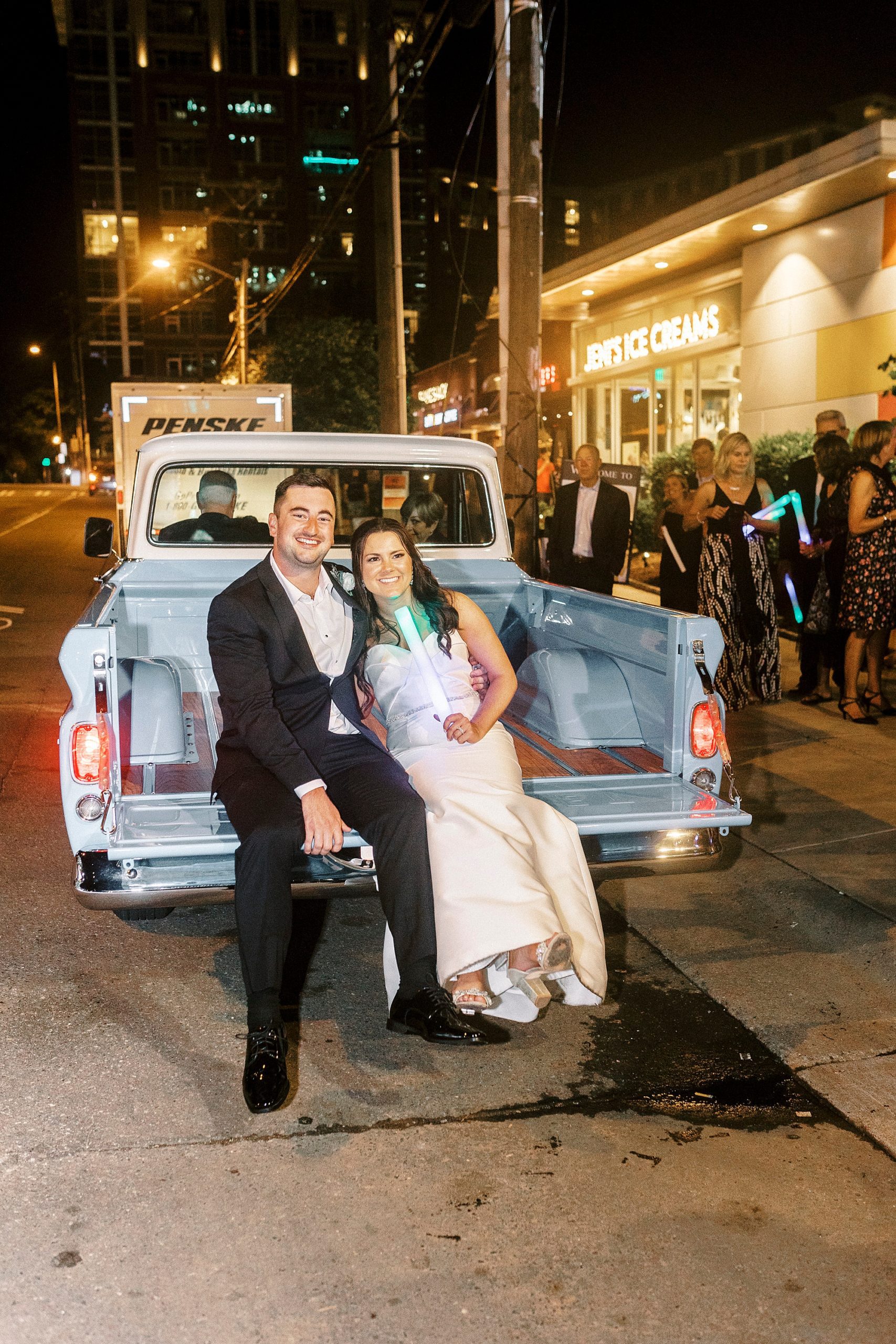 bride and groom sit on back of blue pickup truck outside Byron's South End