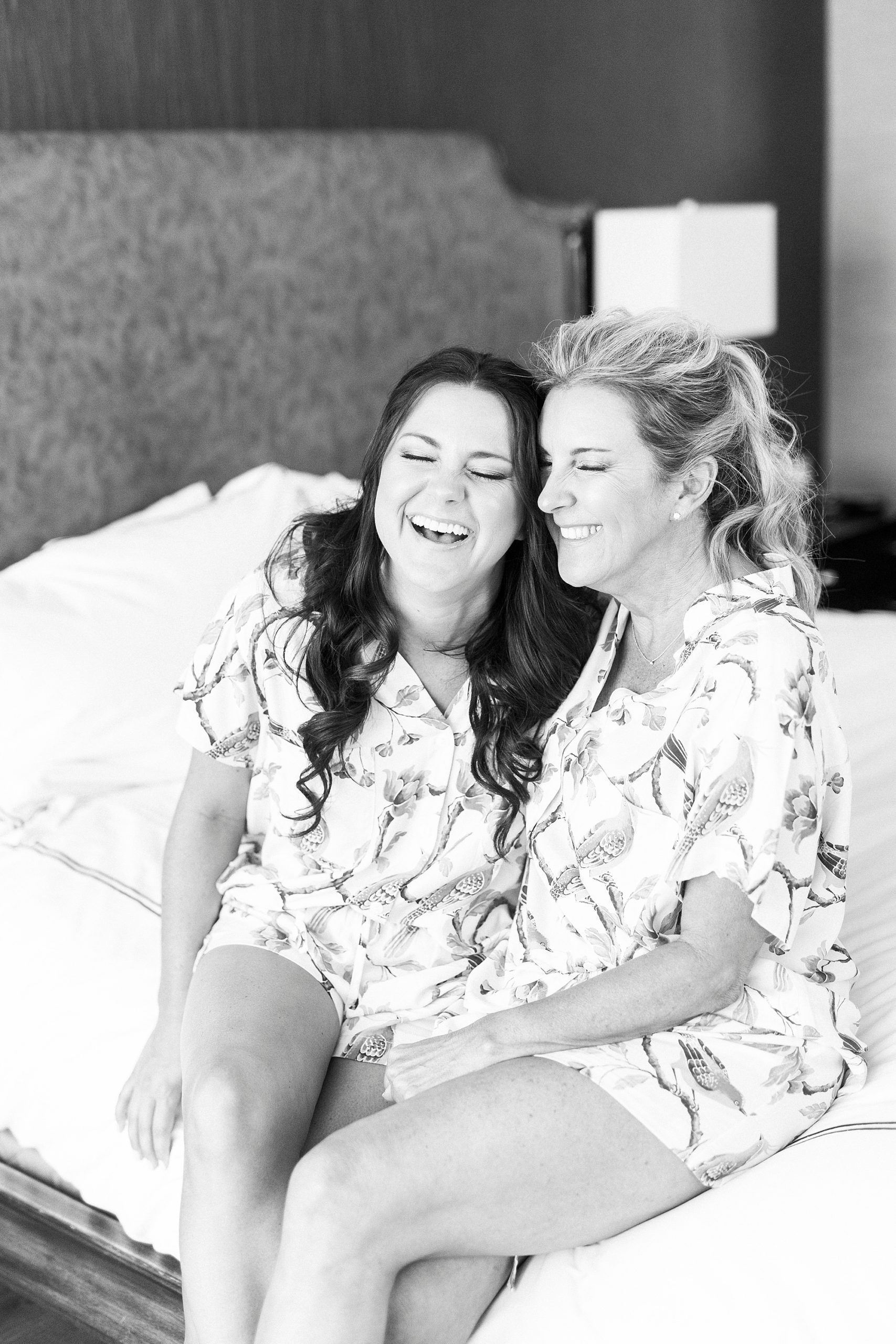 bride laughs with bridesmaid on bed at Kimpton Tyron Park