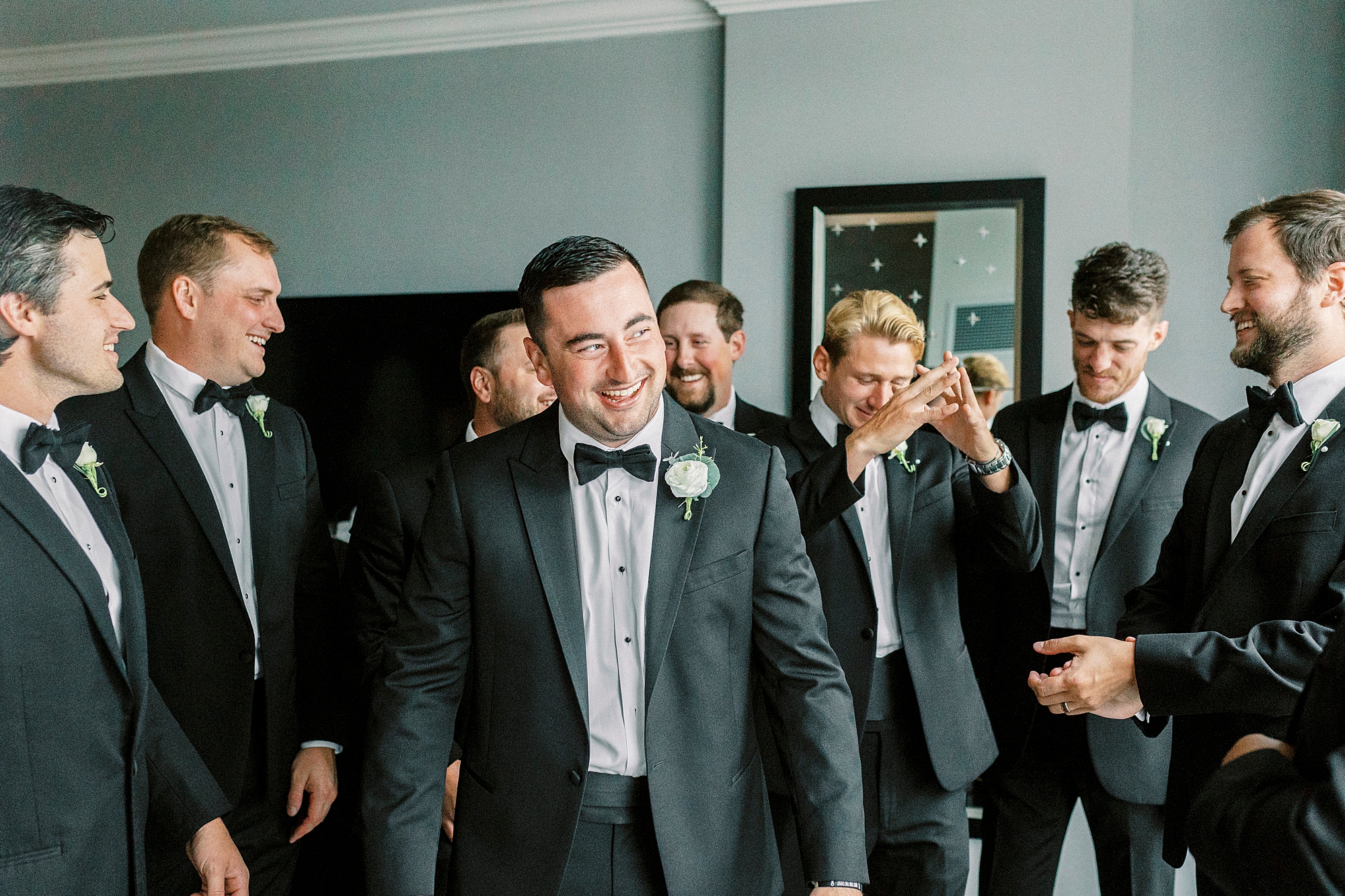 groom in tux laughs with groomsmen at Kimpton Tyron Park before Charlotte NC wedding
