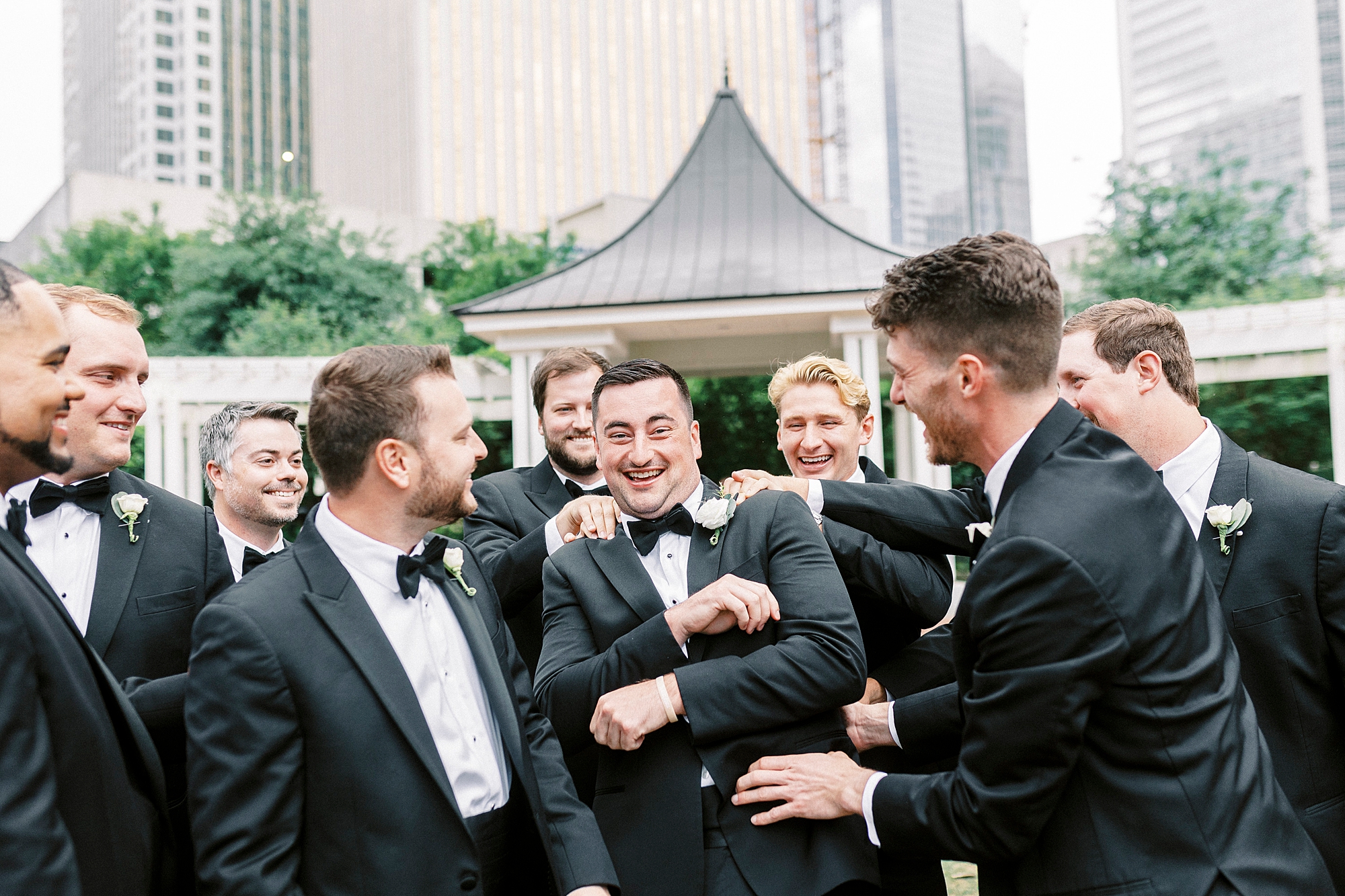 groom laughs with groomsmen in Charlotte park