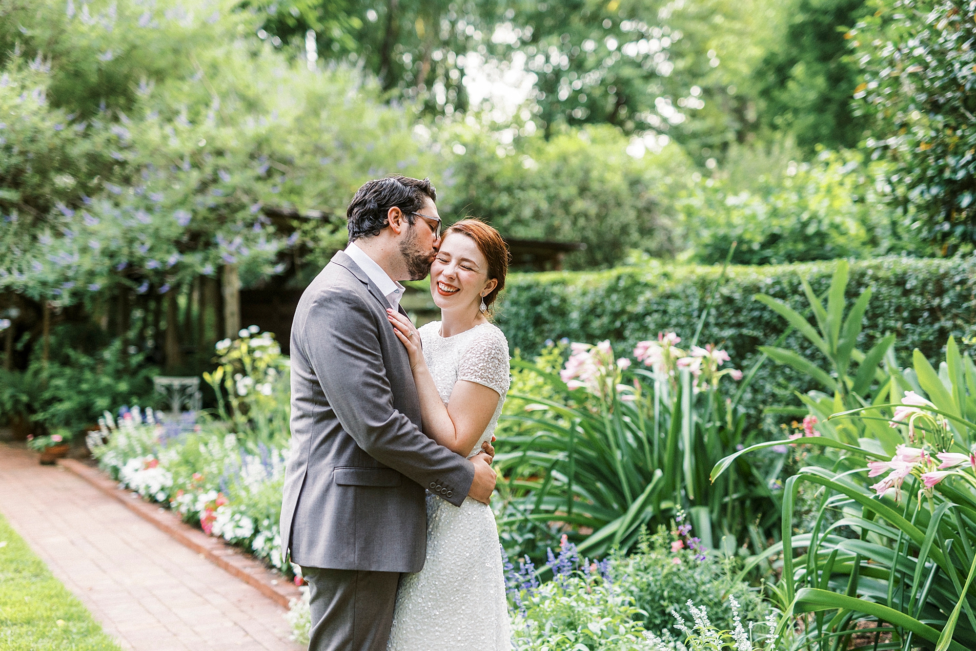 man leans to kiss wife during Wing Haven Garden anniversary session 