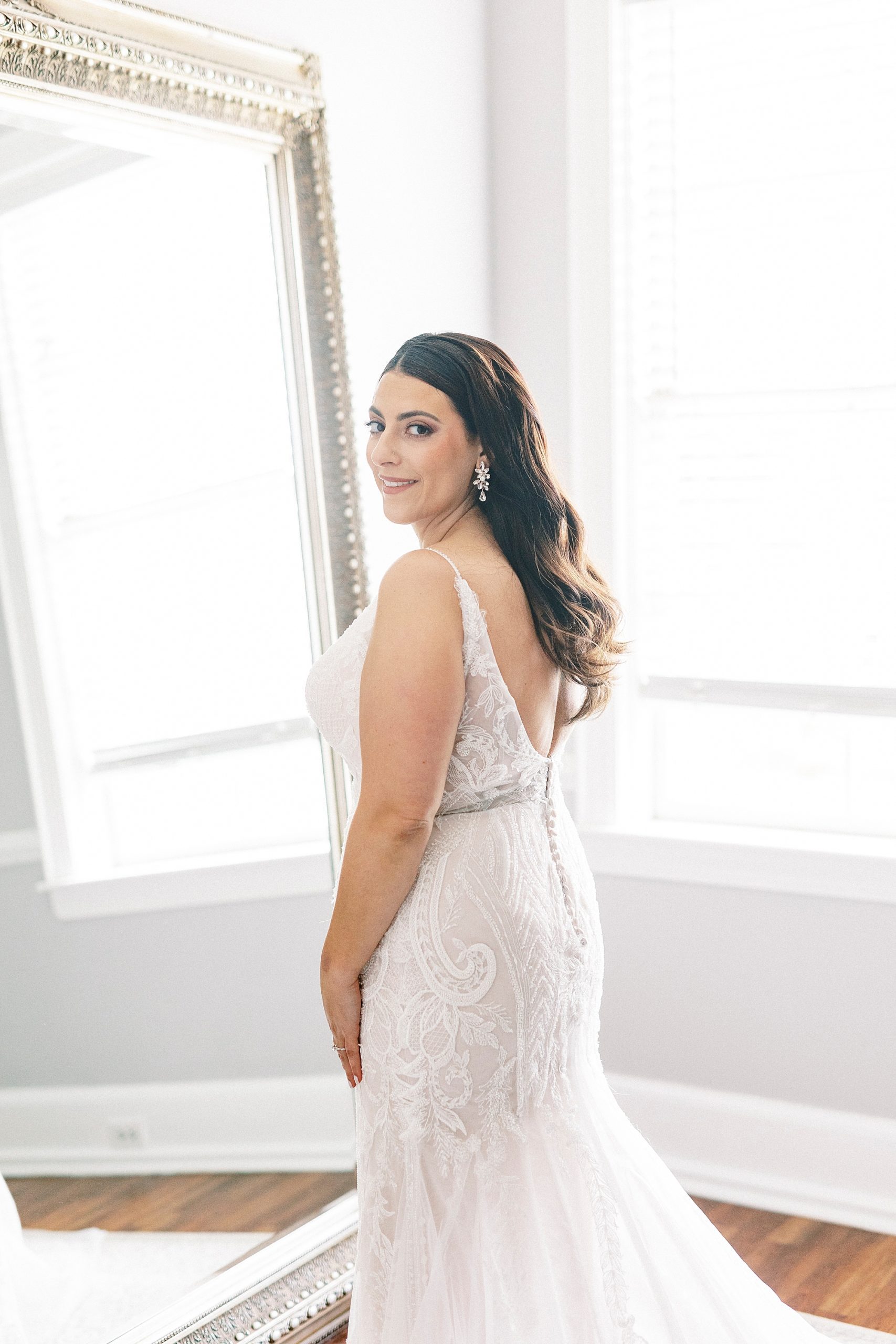 bride looks over shoulder in lace detailed gown