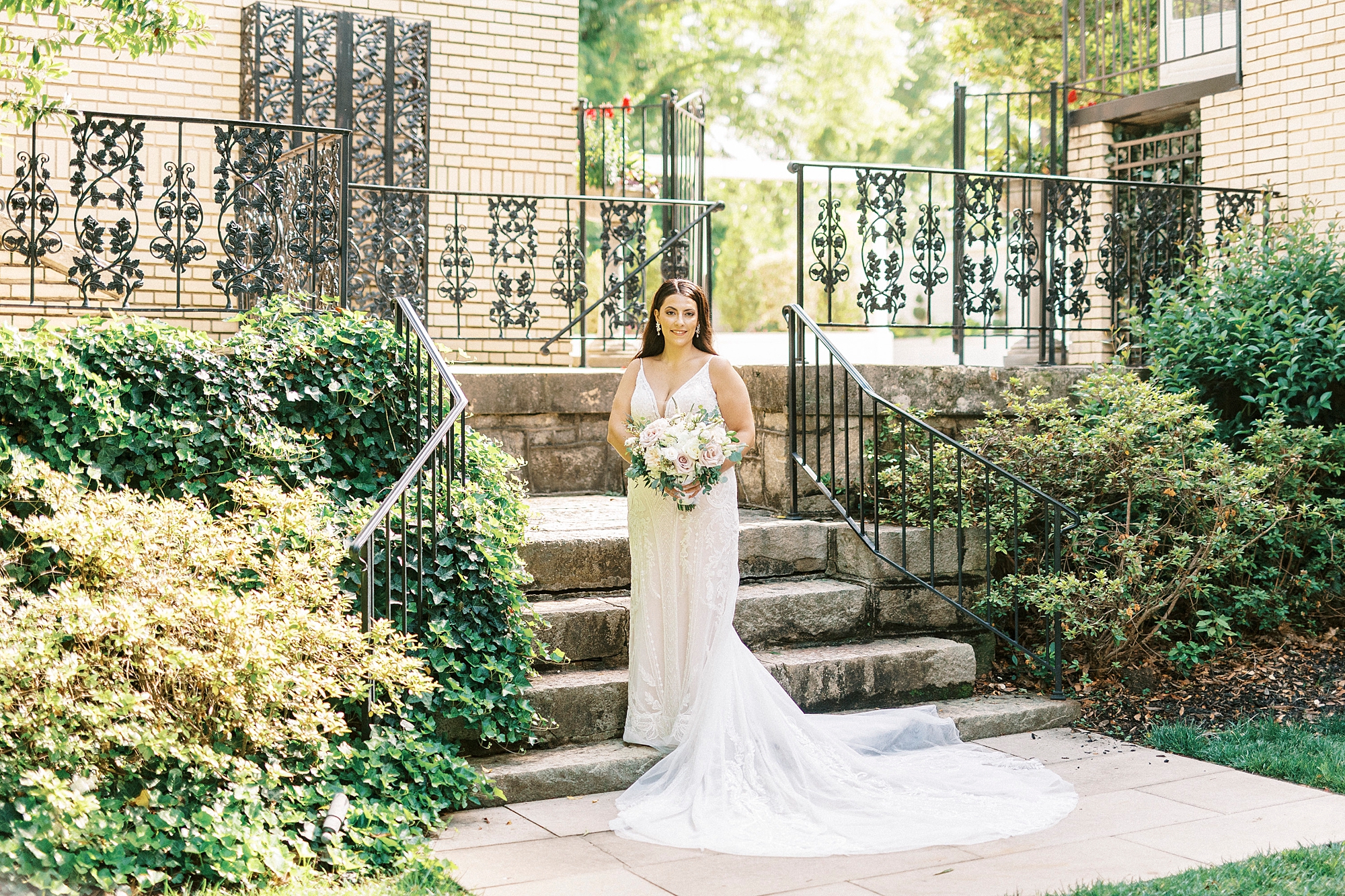 bride stands outside steps at Separk Mansion holding bouquet by hip