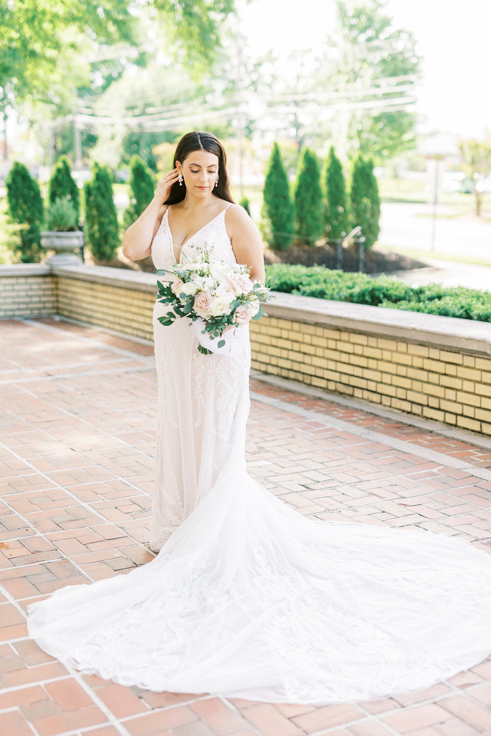 bride stands on brick patio pushing hair behind ear at Separk Mansion