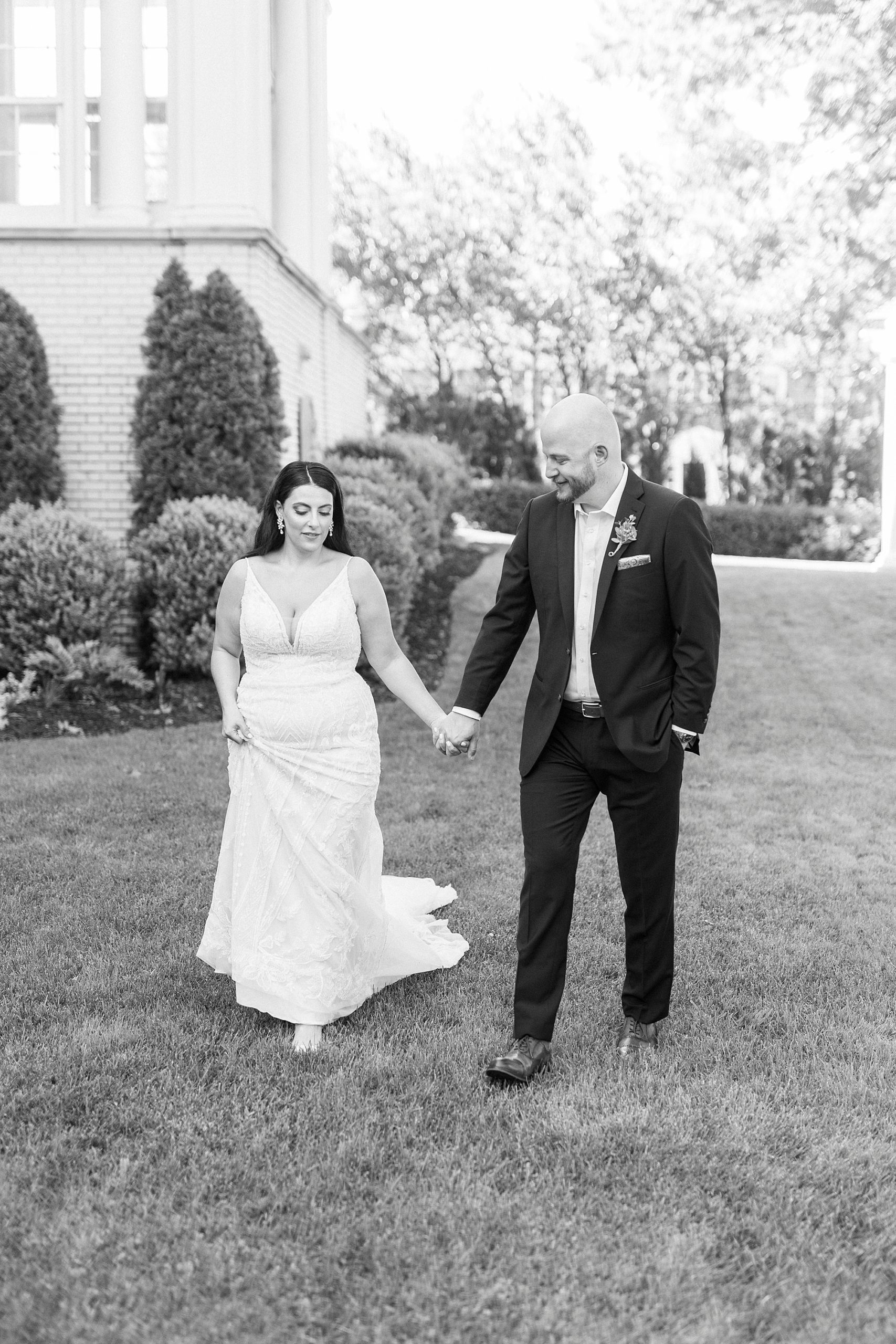 newlyweds hold hands walking across the front lawn at Separk Mansion