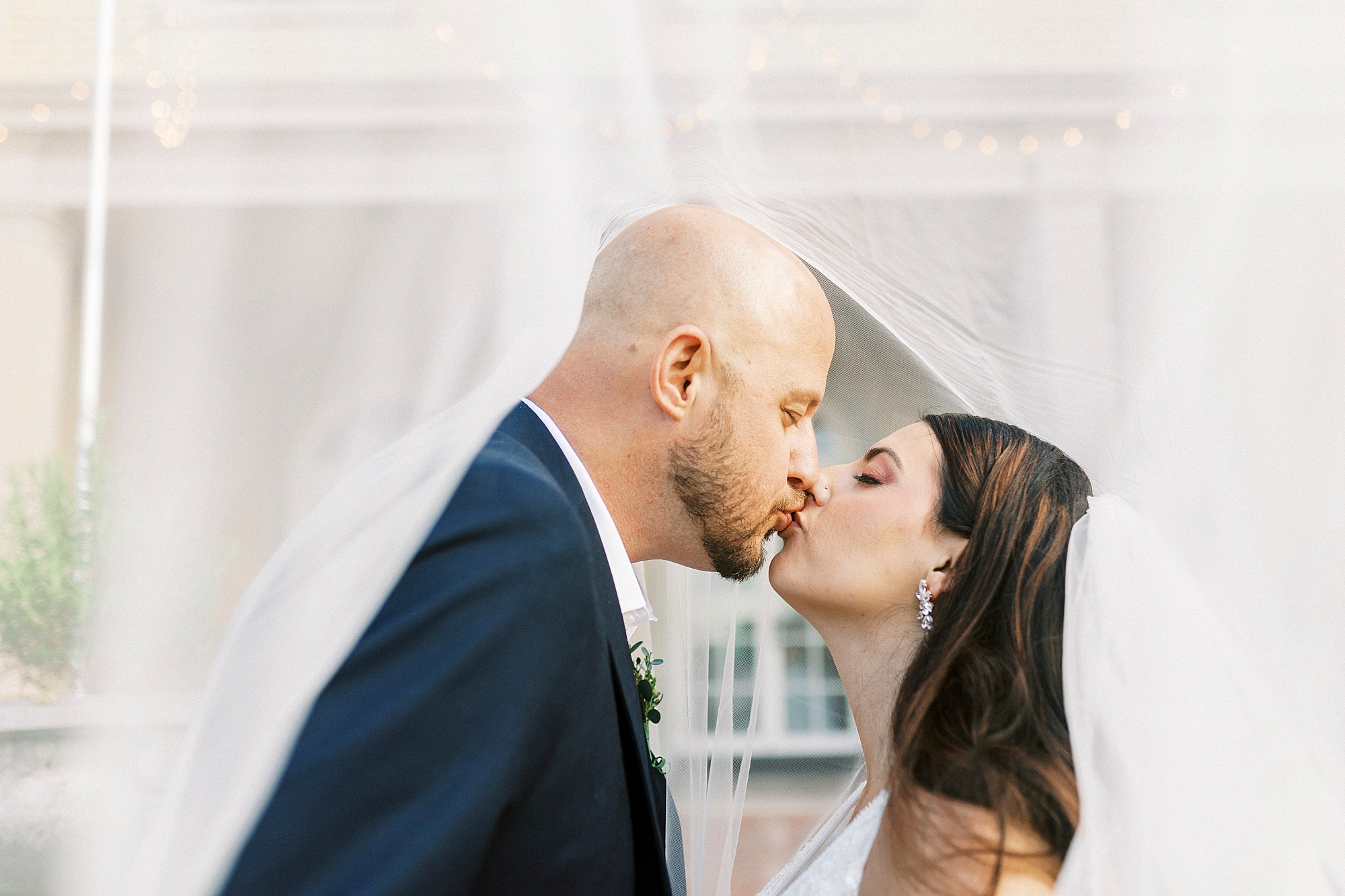 bride and groom kiss under bride's veil