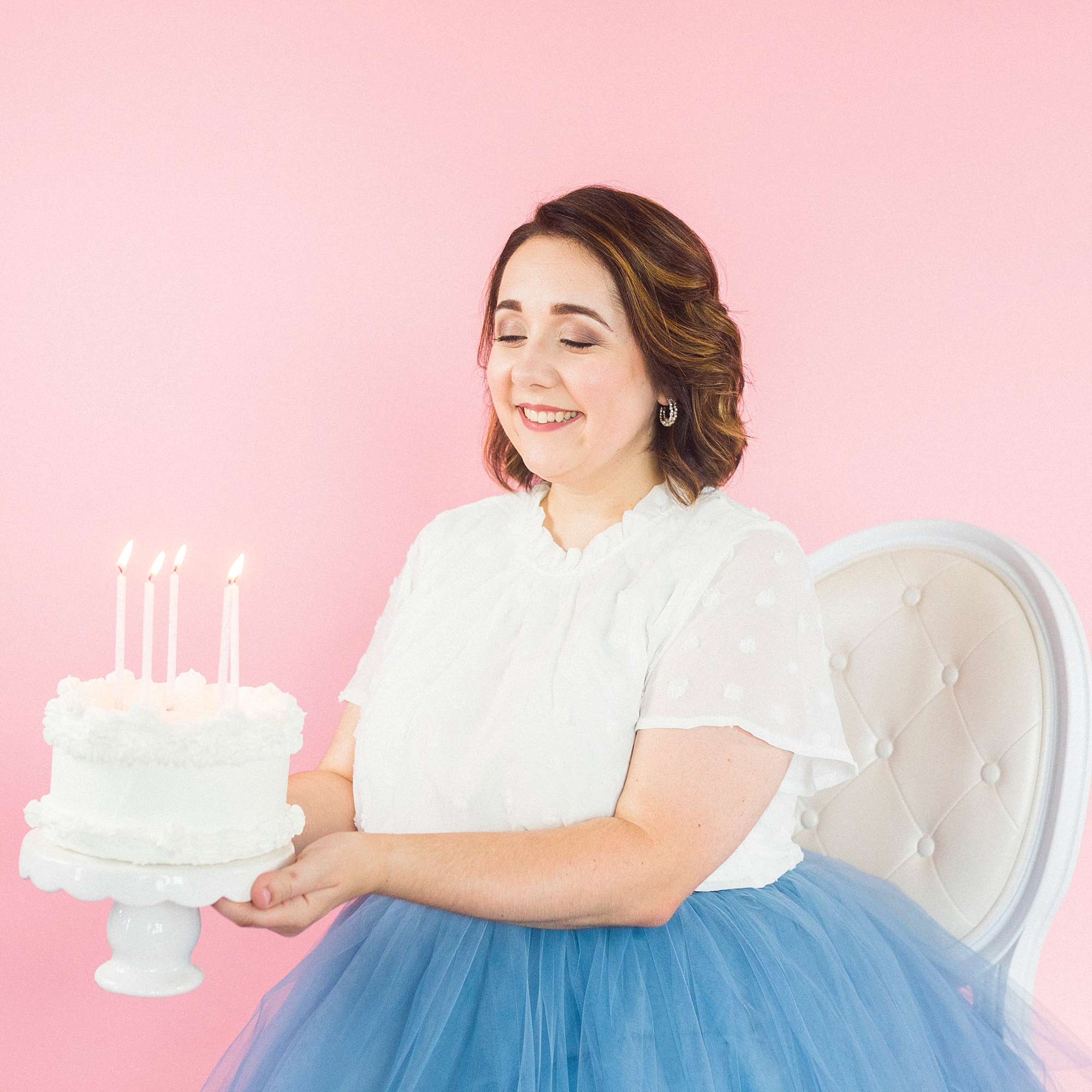 woman holds white cake during 30th birthday portraits with blue skirt