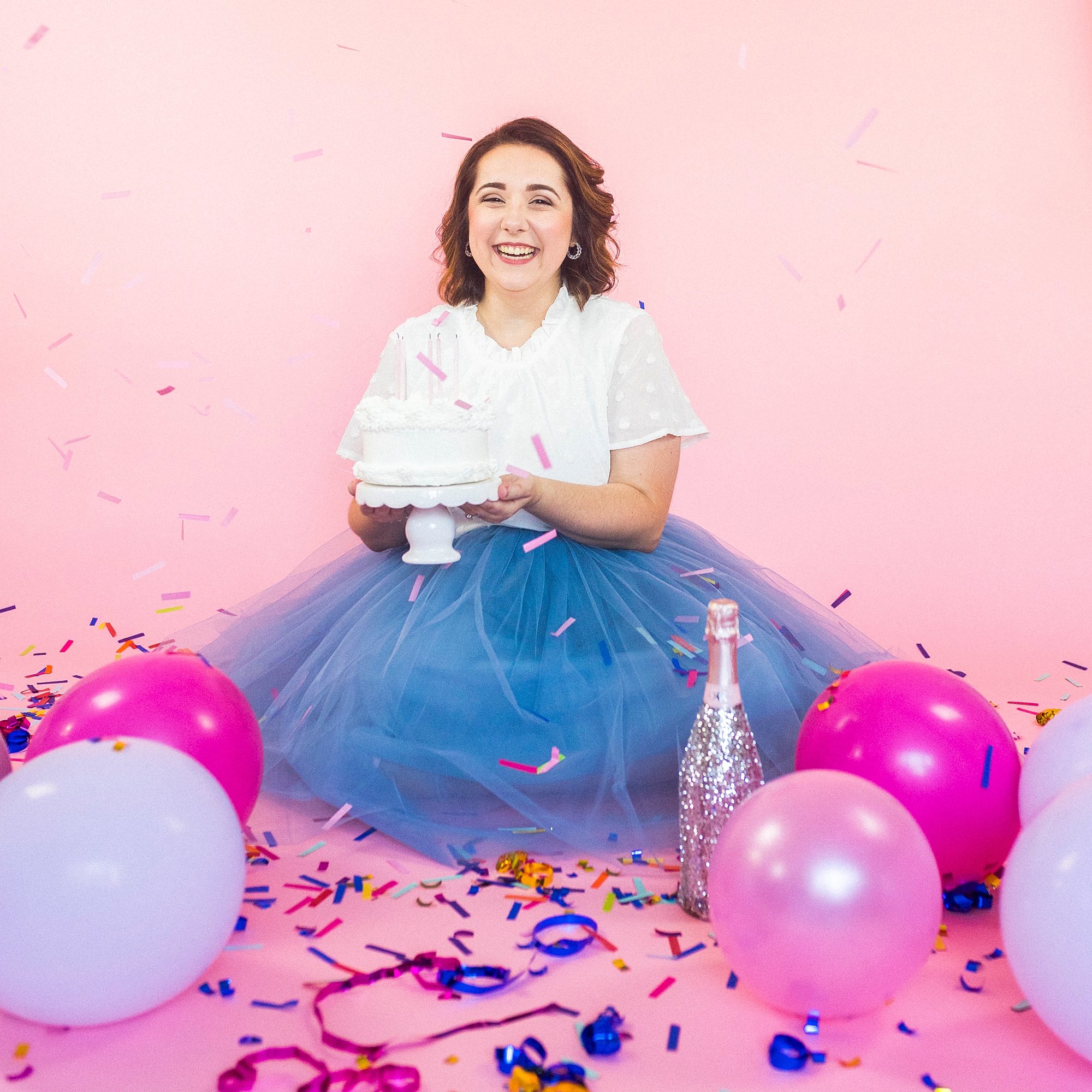 birthday girl holds cake on pink backdrop during 30th birthday portraits
