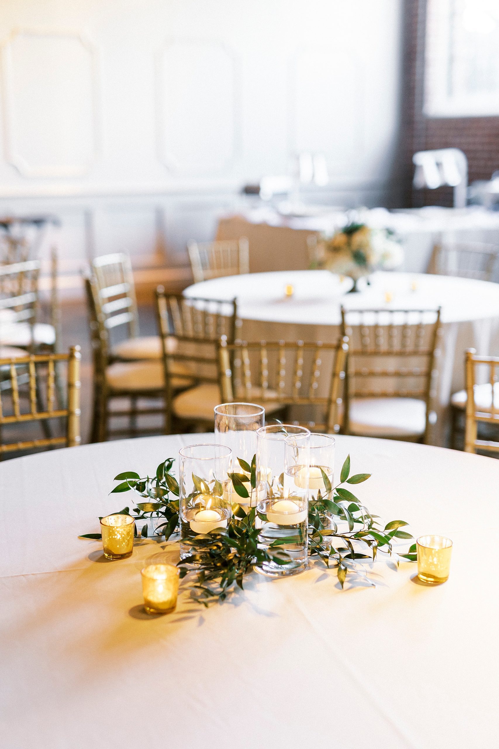 simple centerpieces with gold candles and greenery at Byron's South End