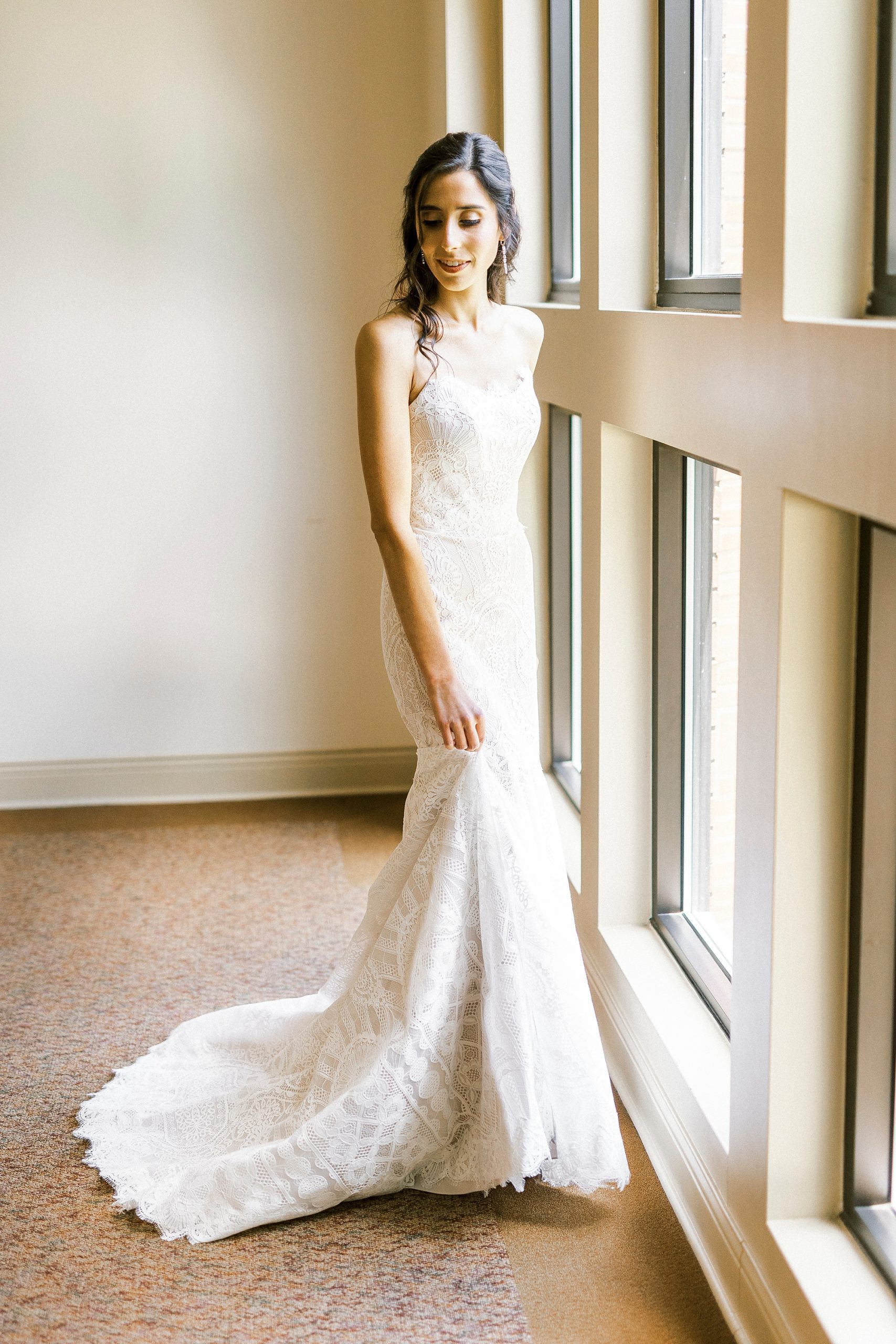 bride poses in wedding dress by window in Charlotte NC
