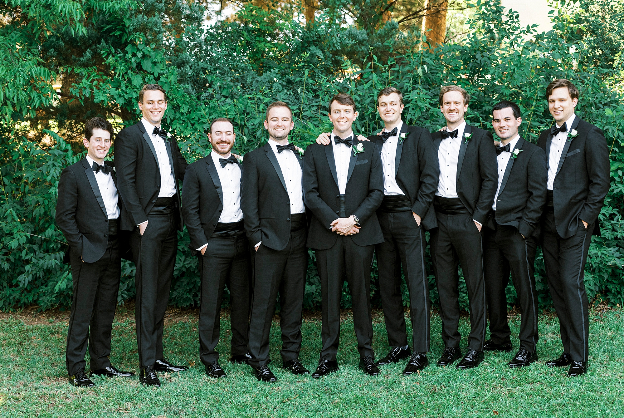 groom stands with groomsmen in classic tuxes at Freedom Park