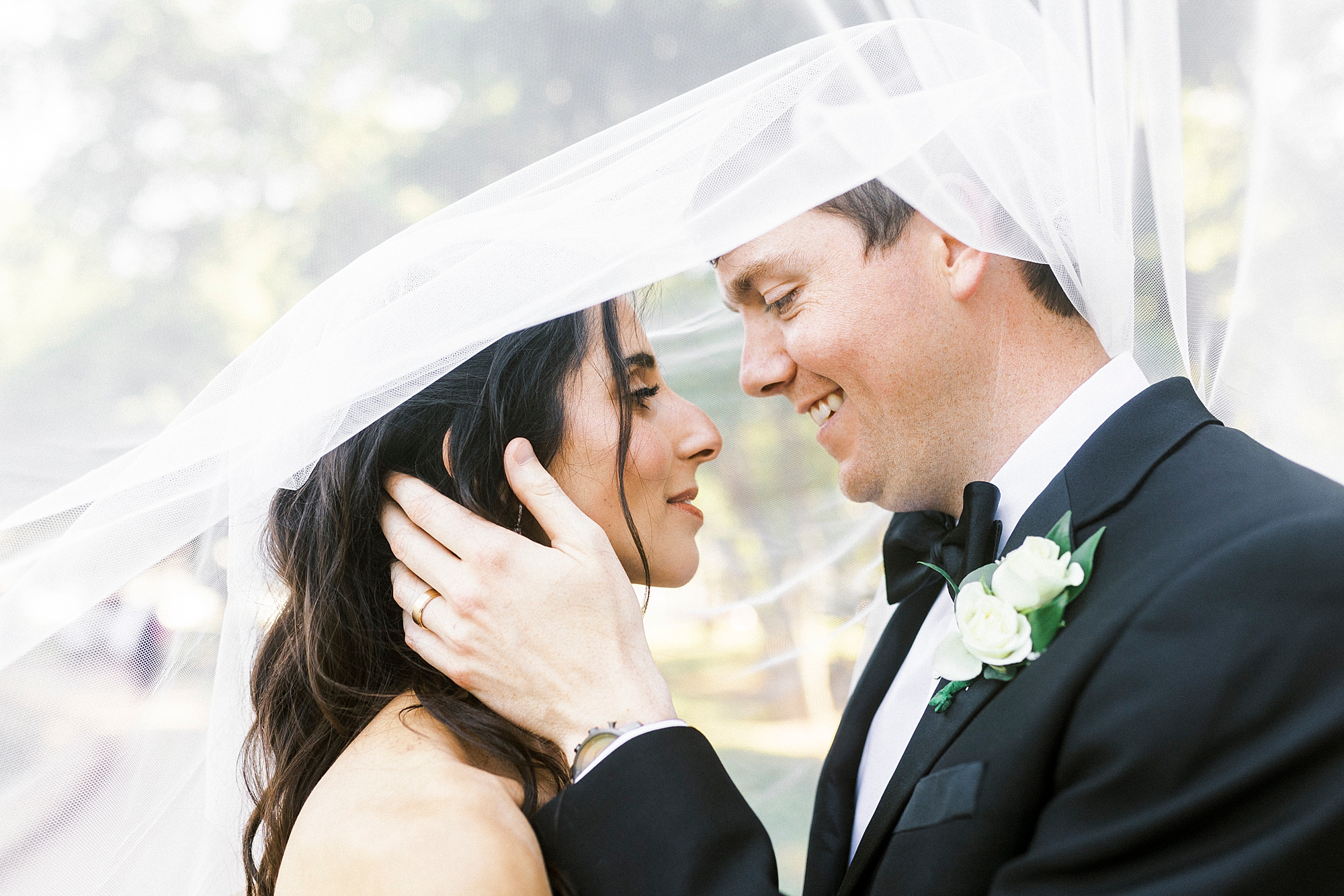 bride and groom smile under bride's veil