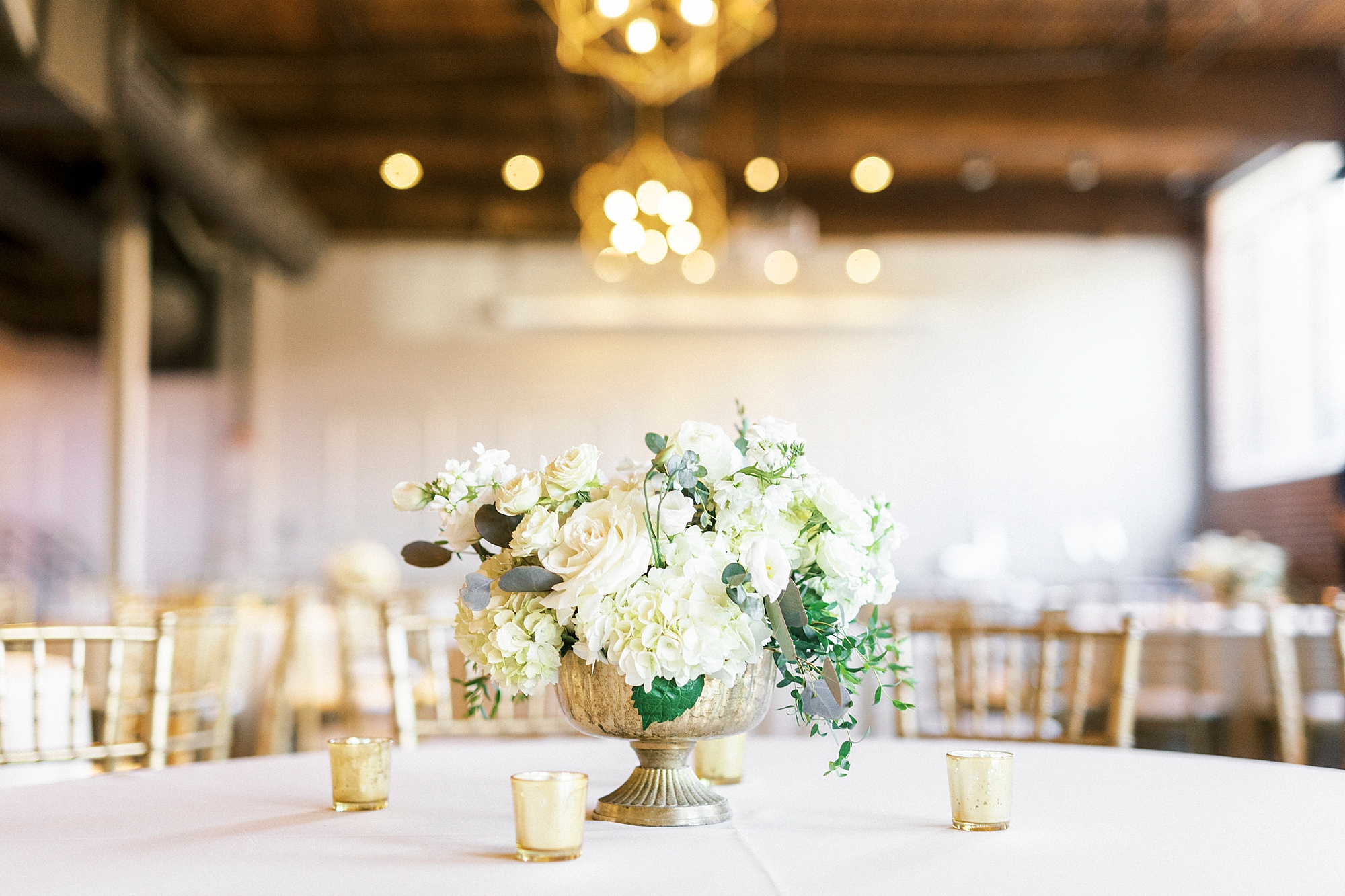 all-white floral centerpieces in gold vessels at Byron's South End