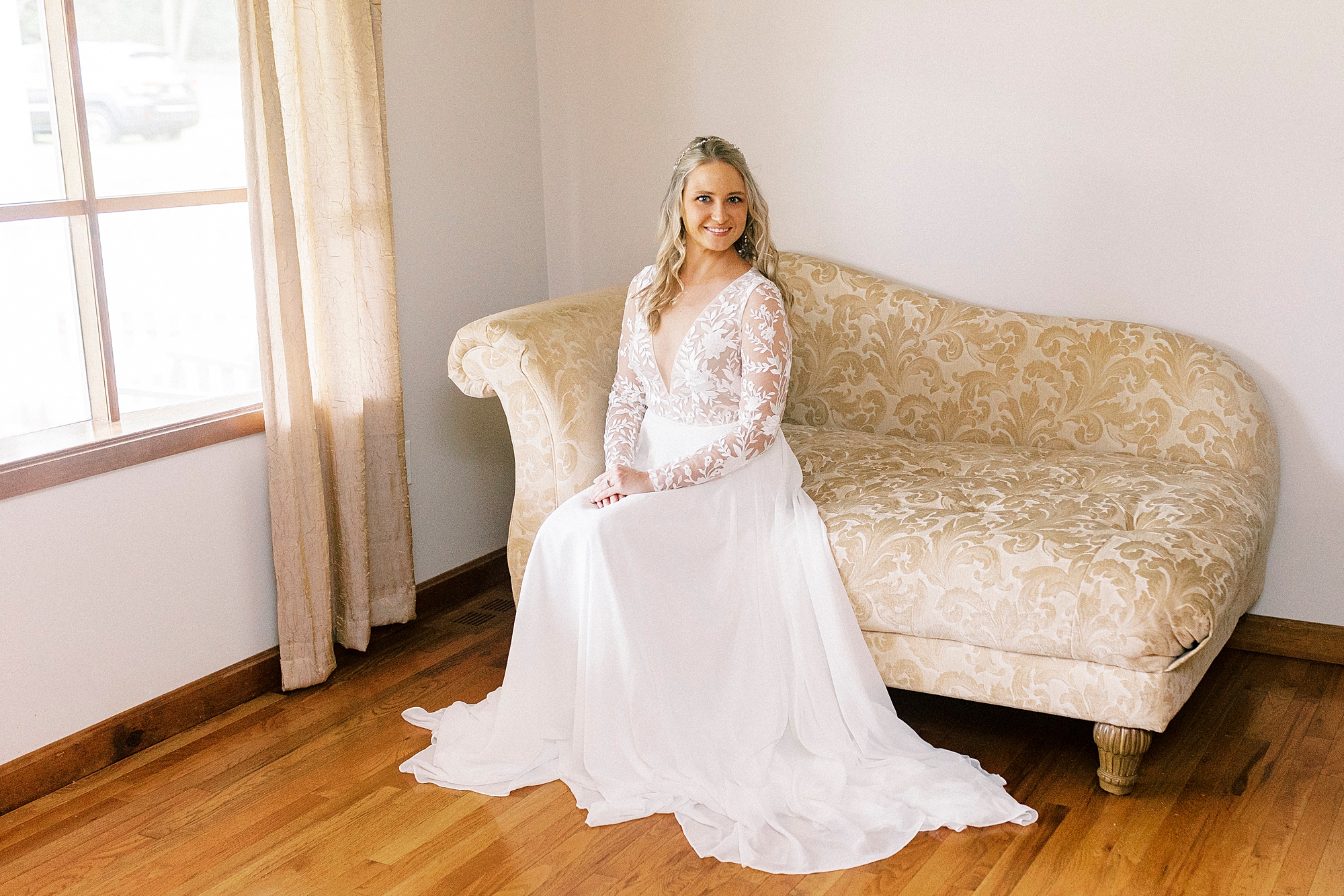 bride sits on gold and ivory couch in Lenoir home