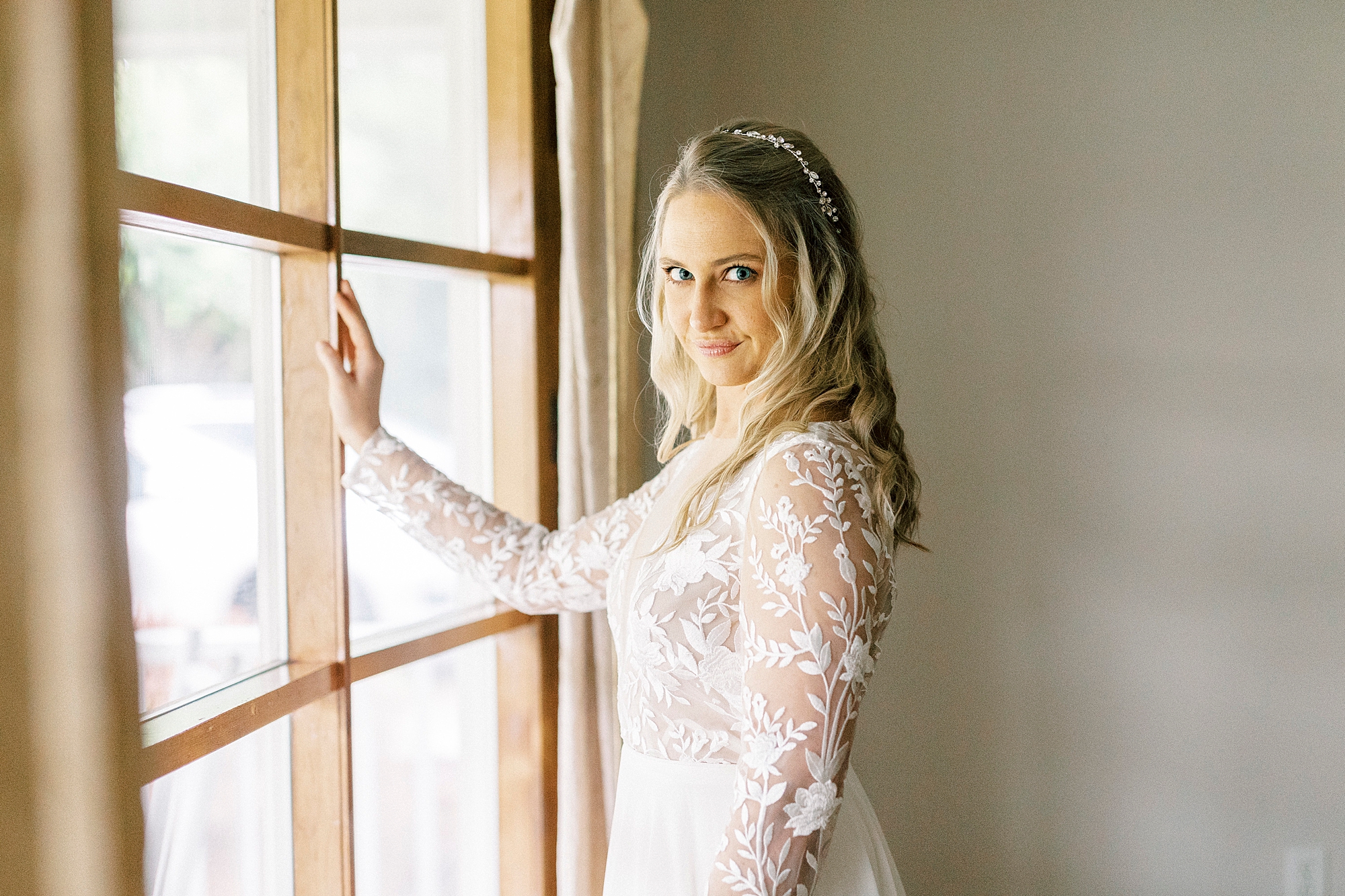 bride leans against wooden window frame at home