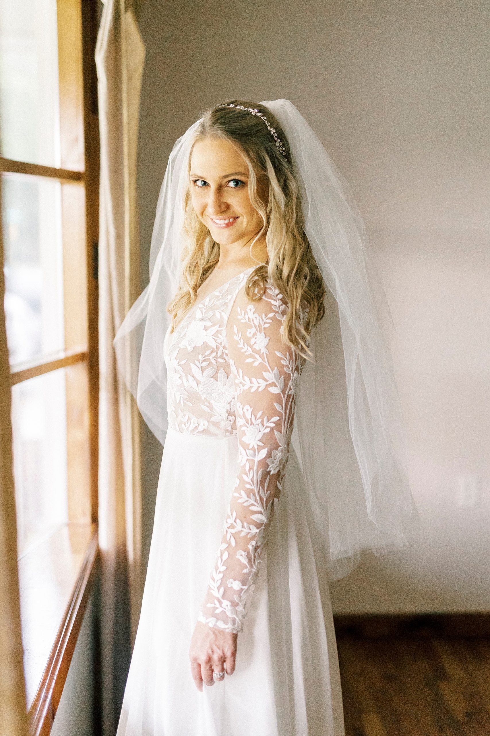 bride smiles looking over shoulder with veil draped around her shoulders 