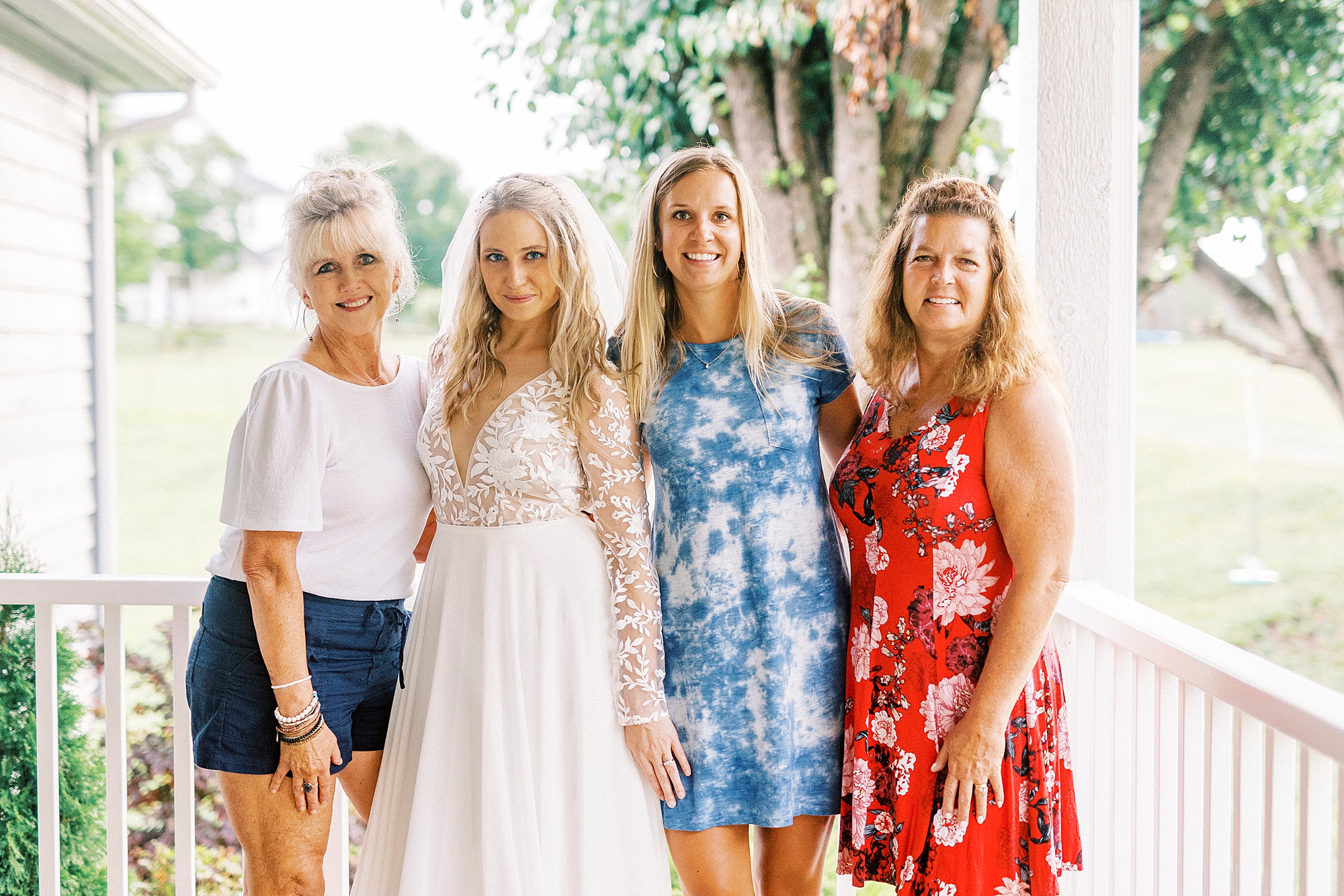 bride smiles with mother and sisters during bridal portraits