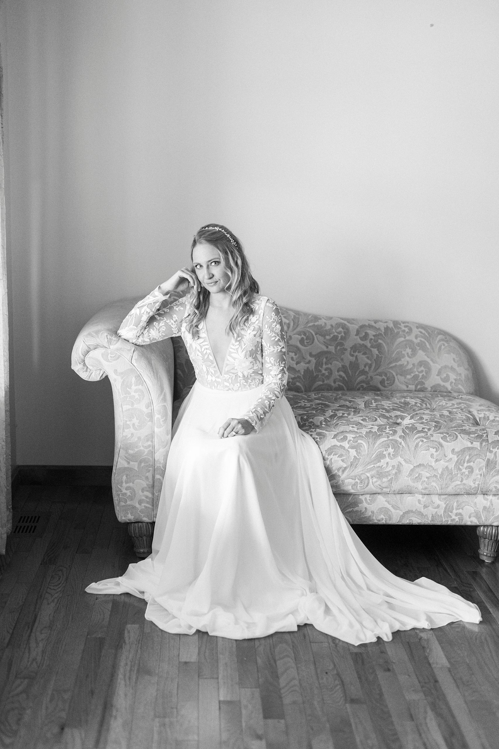 bride leans against back of couch in wedding gown during bridal portraits 