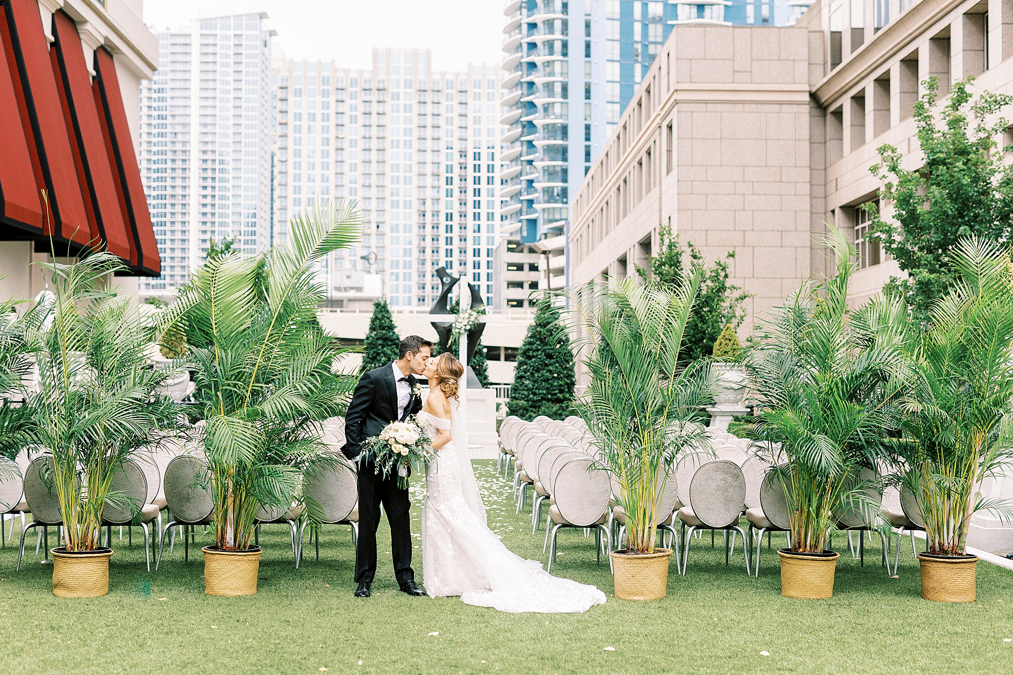 bride and groom kiss by end of aisle with ferns at The Grand Bohemian Hotel