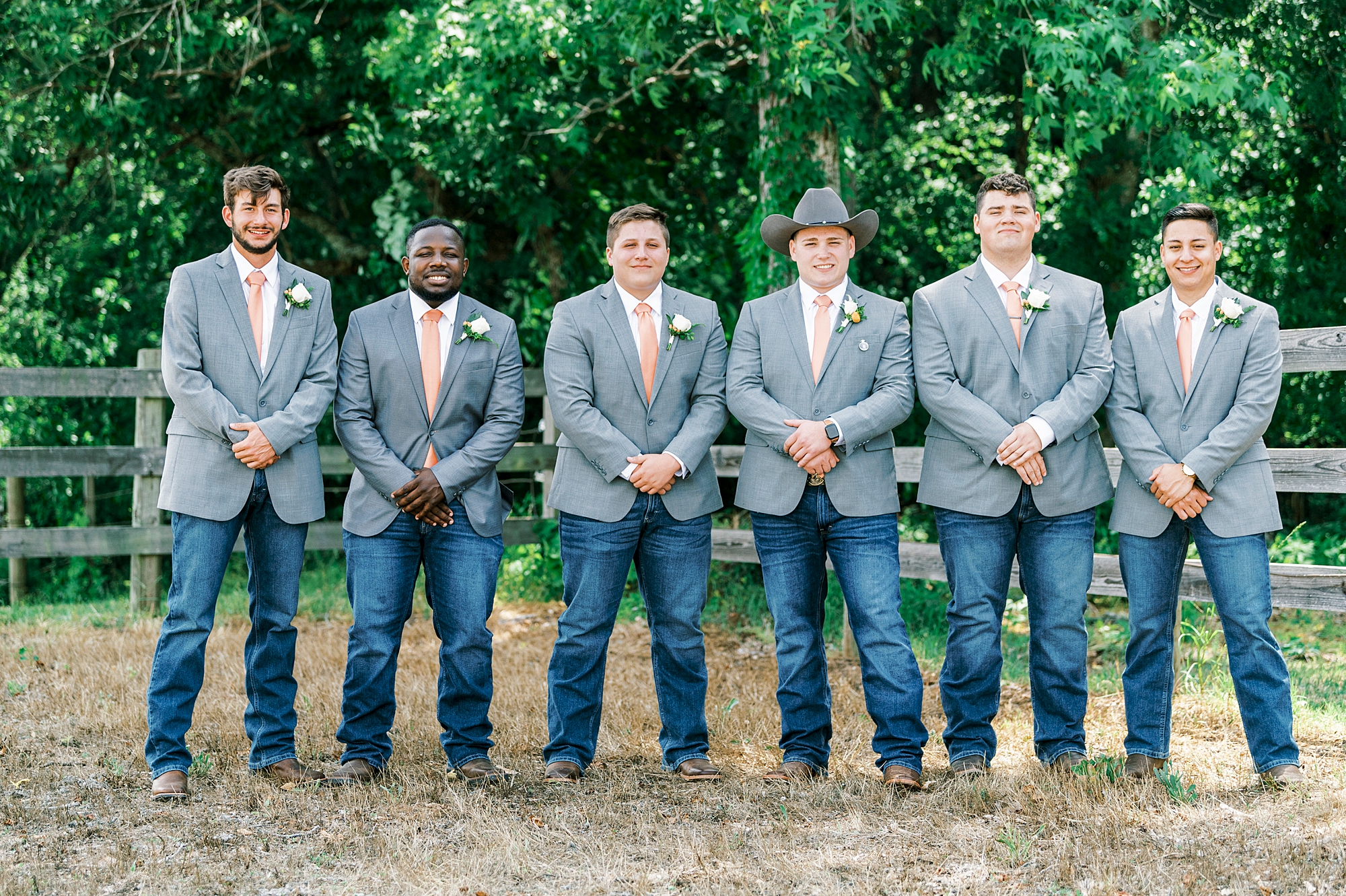 groom stands with groomsmen in suit jackets with jeans at The Stable at Riverview