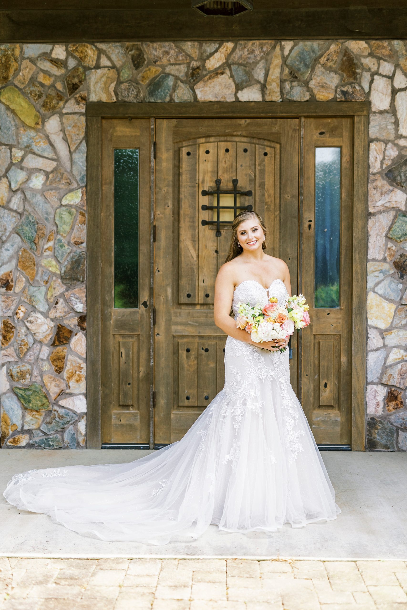 bride poses outside wooden door at The Stable at Riverview