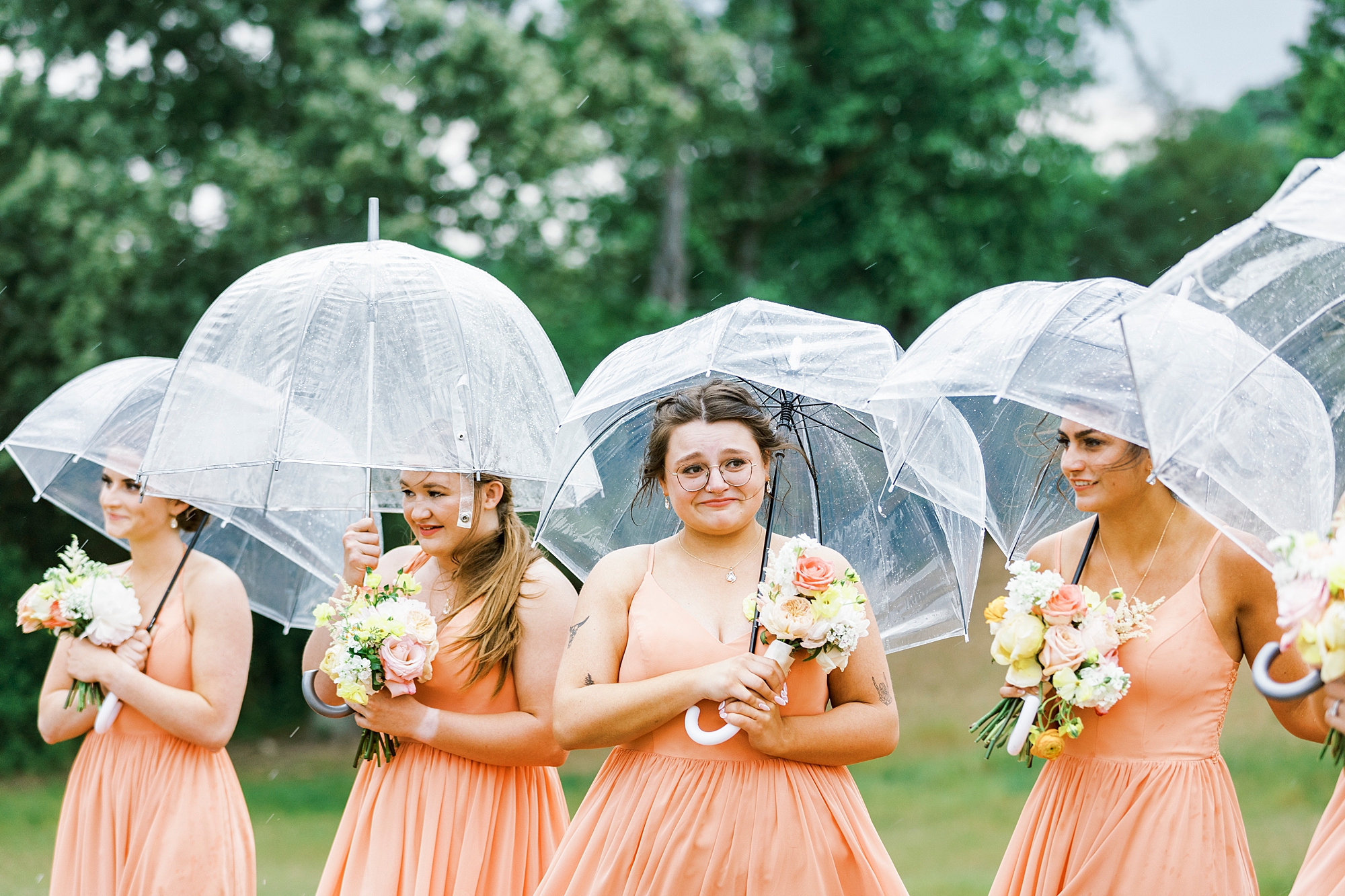 bridesmaid holds clear umbrella during rainy wedding ceremony at The Stable at Riverview