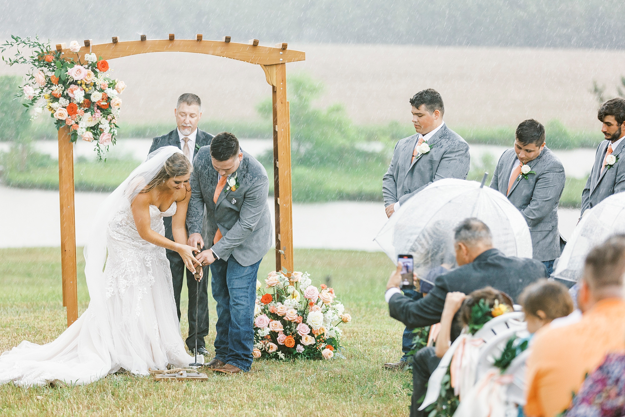 couple digs up bourbon during rainy wedding ceremony at The Stable at Riverview