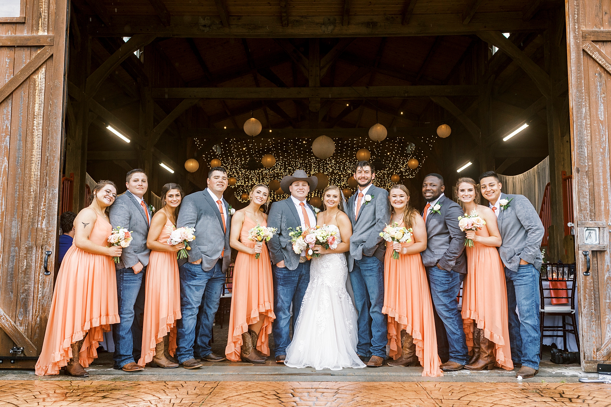newlyweds stand with wedding party inside barn at The Stable at Riverview