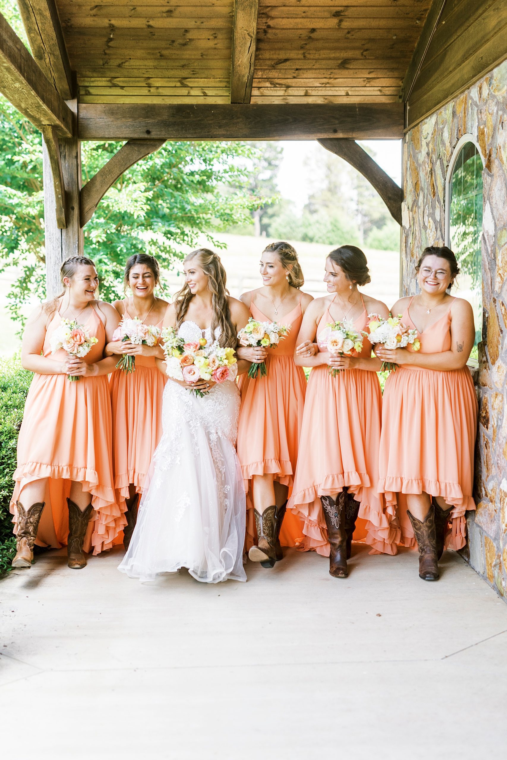 bride stands with bridesmaids in coral gowns