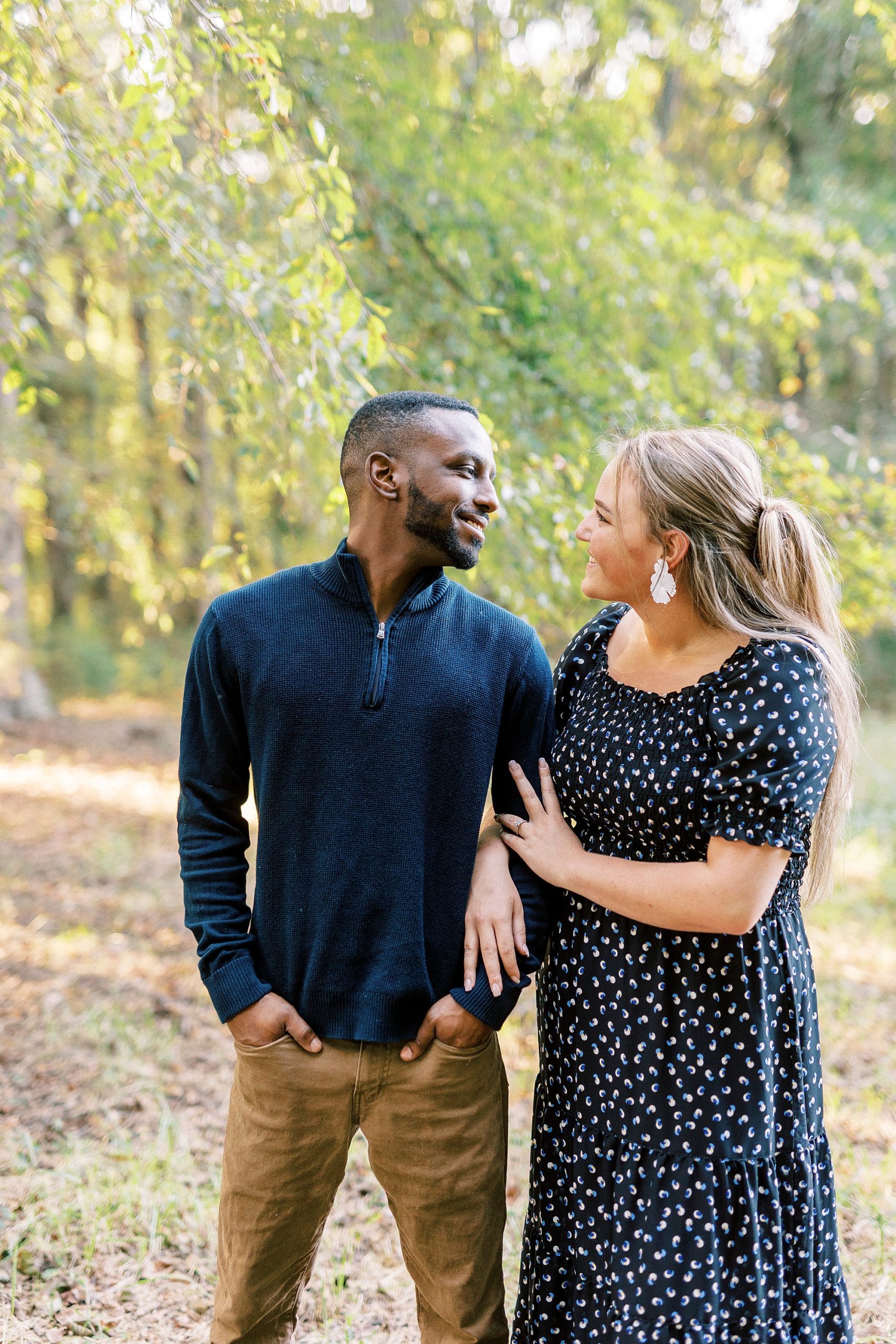 engaged couple stand together in navy outfits during fall Bella Terra engagement session
