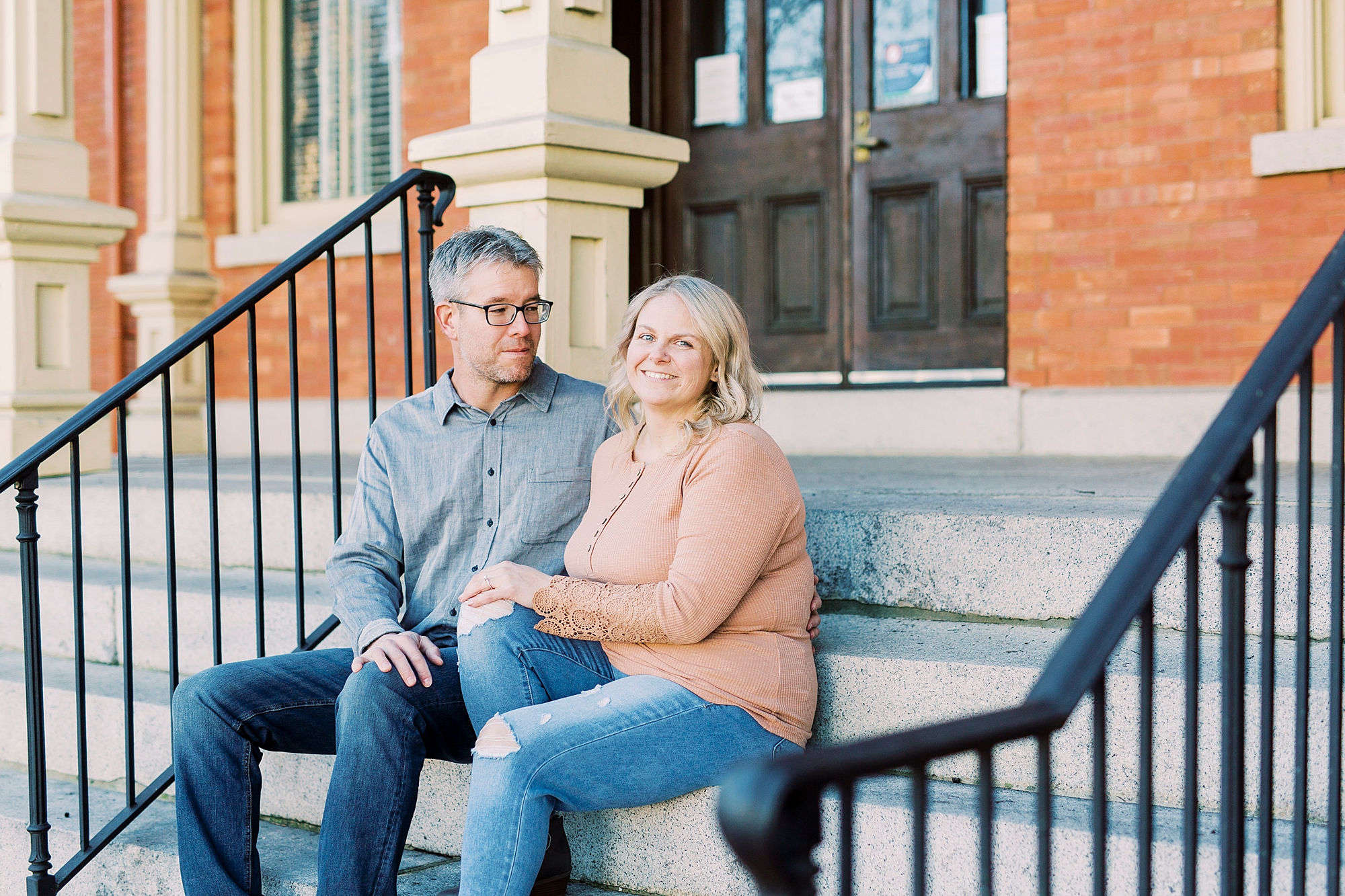 engaged couple sits on steps during Downtown Monroe engagement portraits
