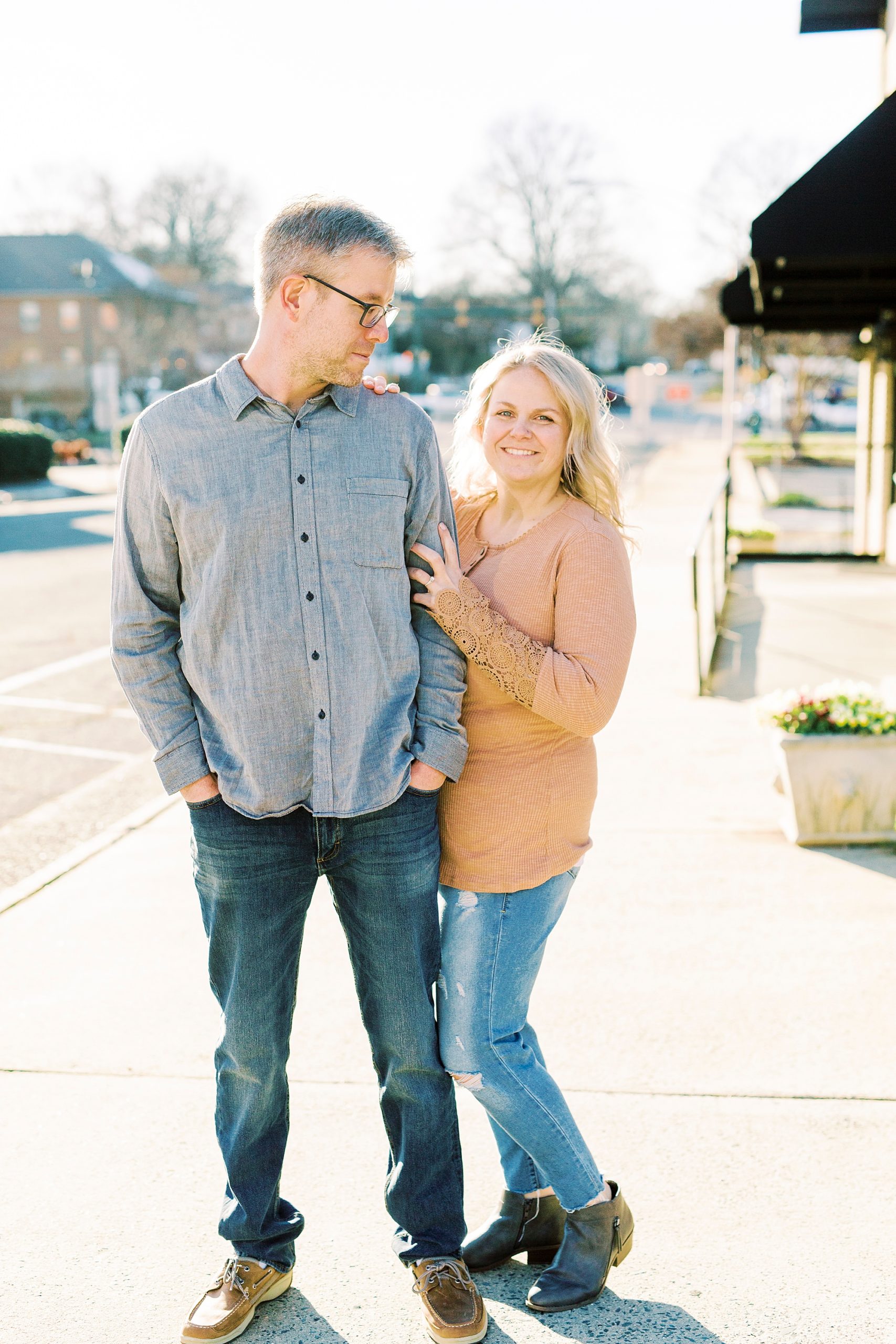 bride holds onto groom's arm during fall Downtown Monroe engagement portraits